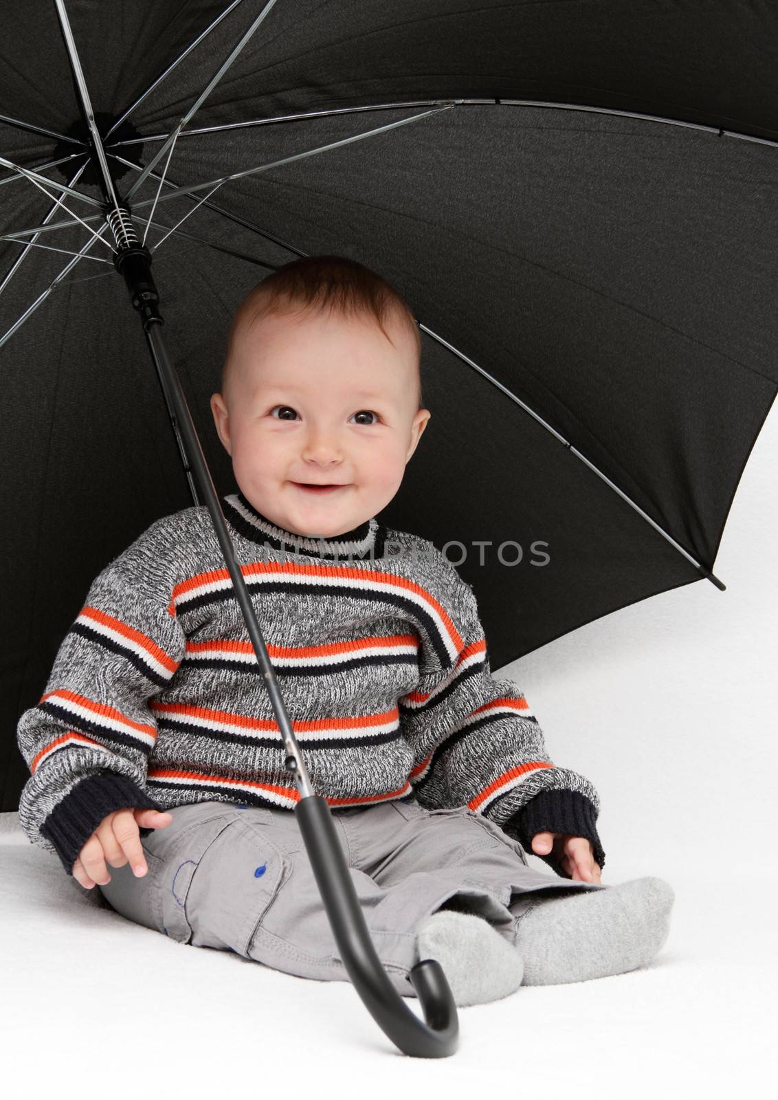 baby boy sitting under umbrella by NikolayK