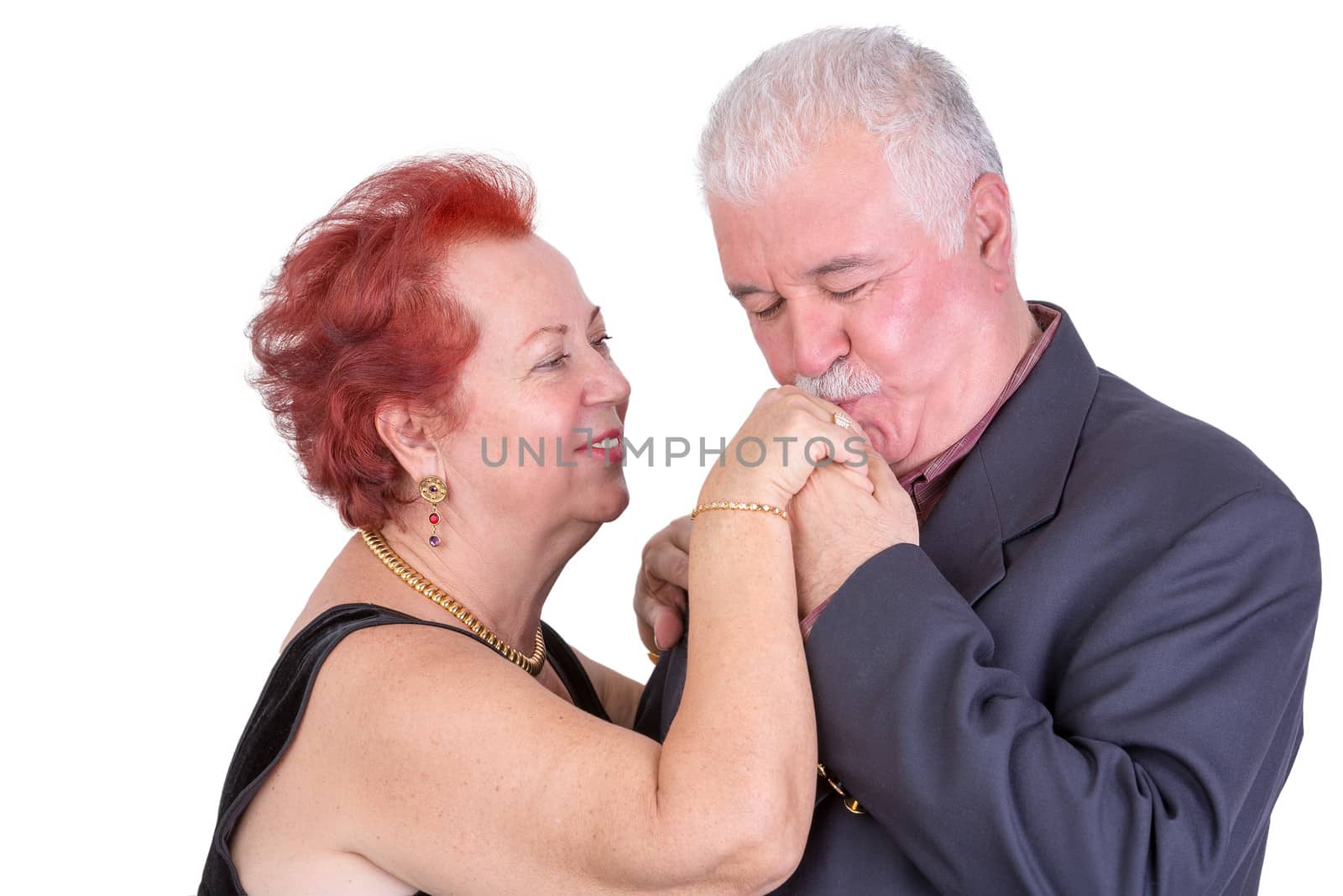 Senior man kissing his wifes hand, both looks happy, perhaps its their anniversary
