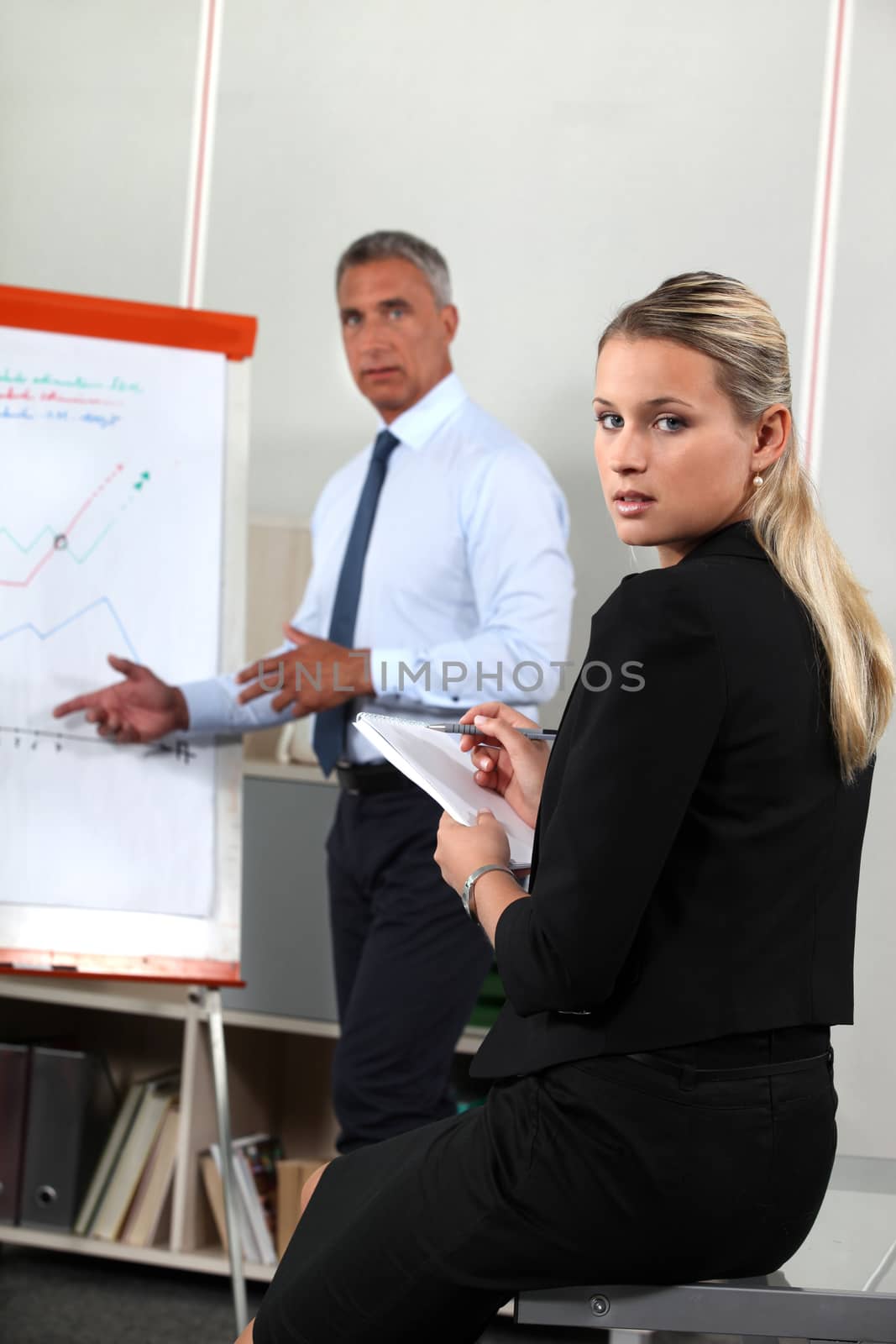 Business people looking at a flipchart by phovoir