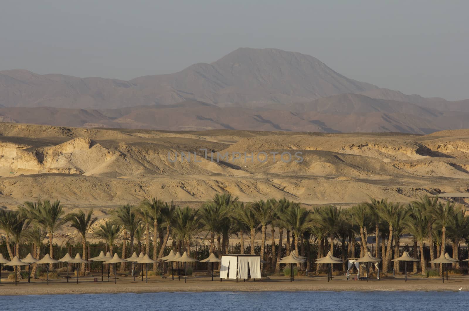 Mountains in a desert with sea and beach in the foreground 