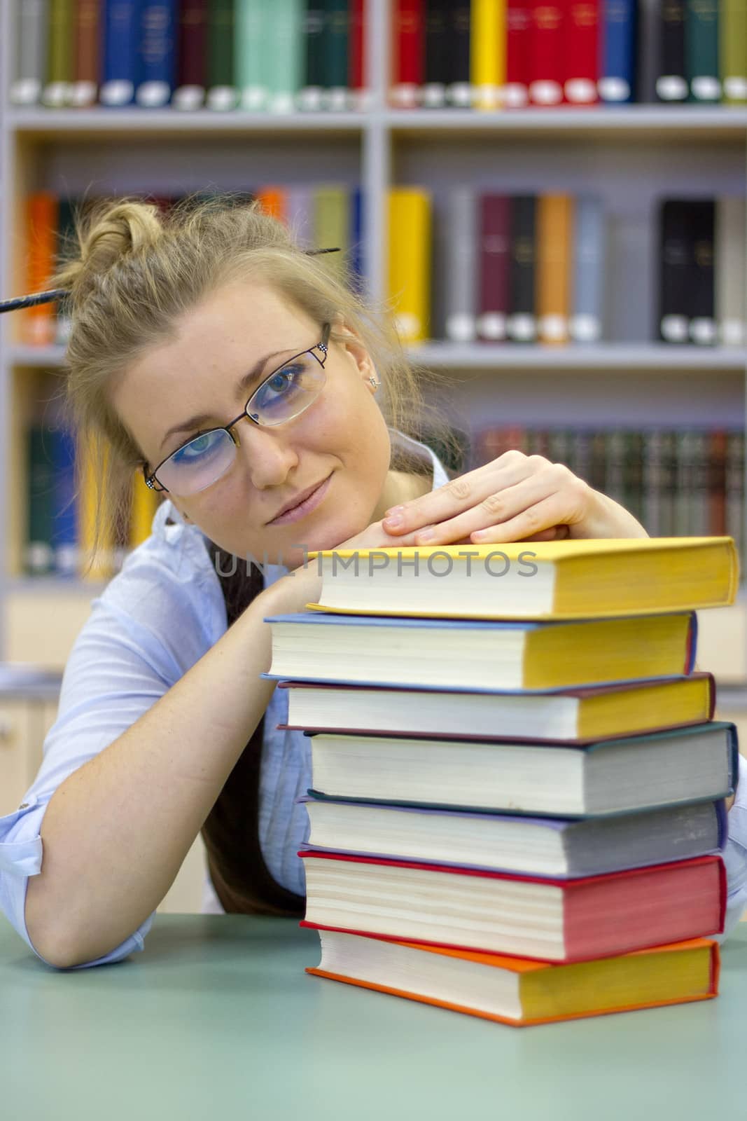 Portrait of clever student with open book reading it in library