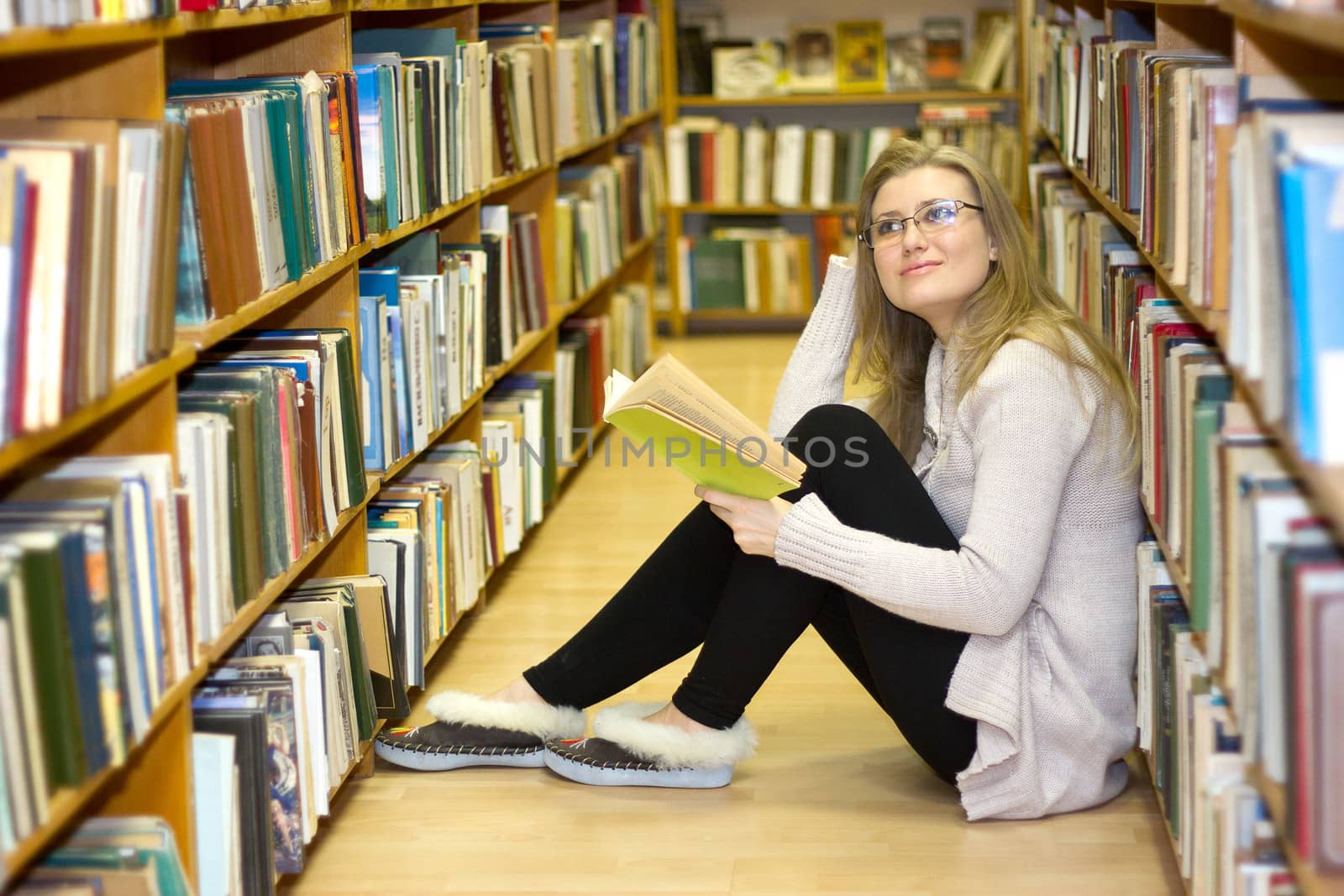 Girl sitting on the floor in the old library of books