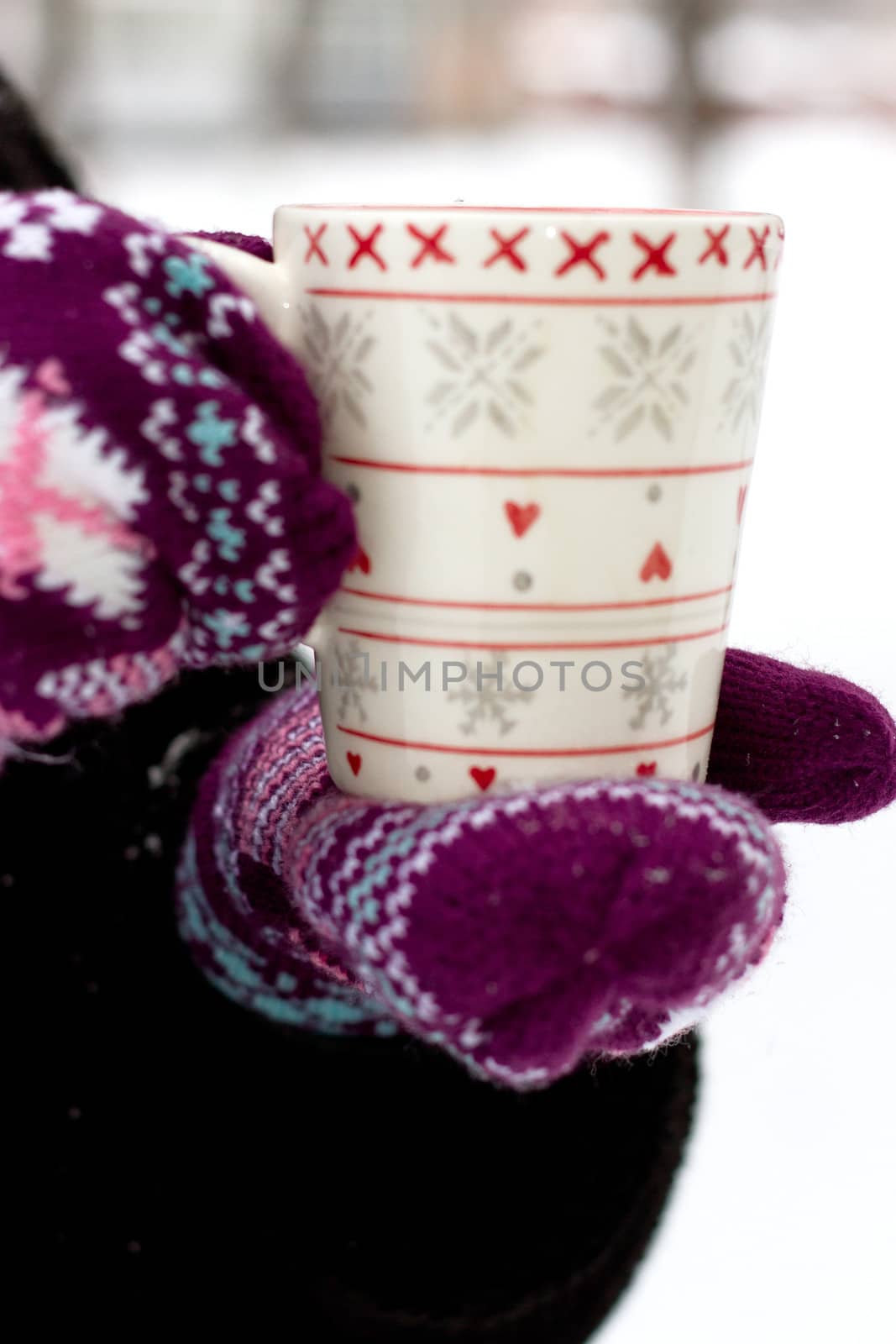 Cozy red gloves hold a mug of hot cocoa on a snowy day