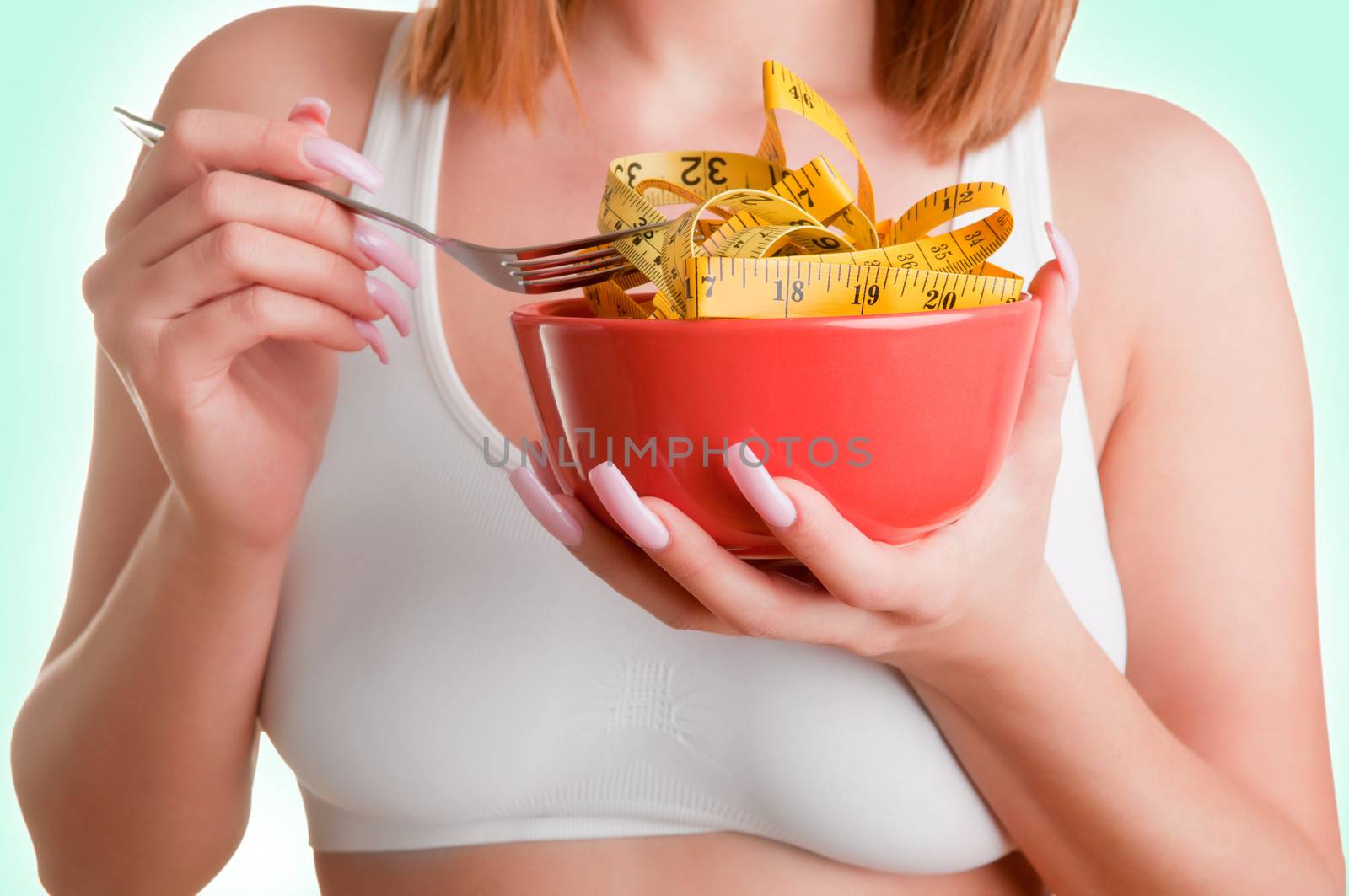 Woman eating a bowl of measruring tapes. Diet concept.