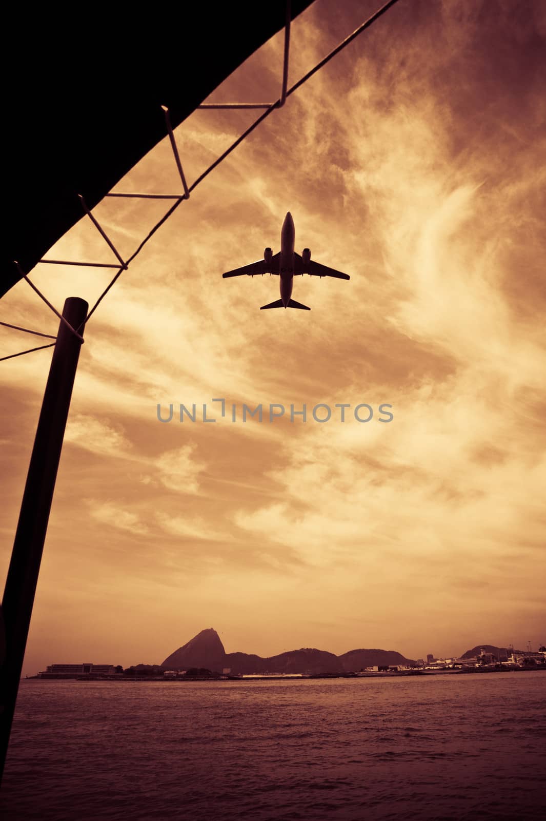 Sepia view of aircraft flying over sea with coastline of Rio de Janeiro in background, Brazil.