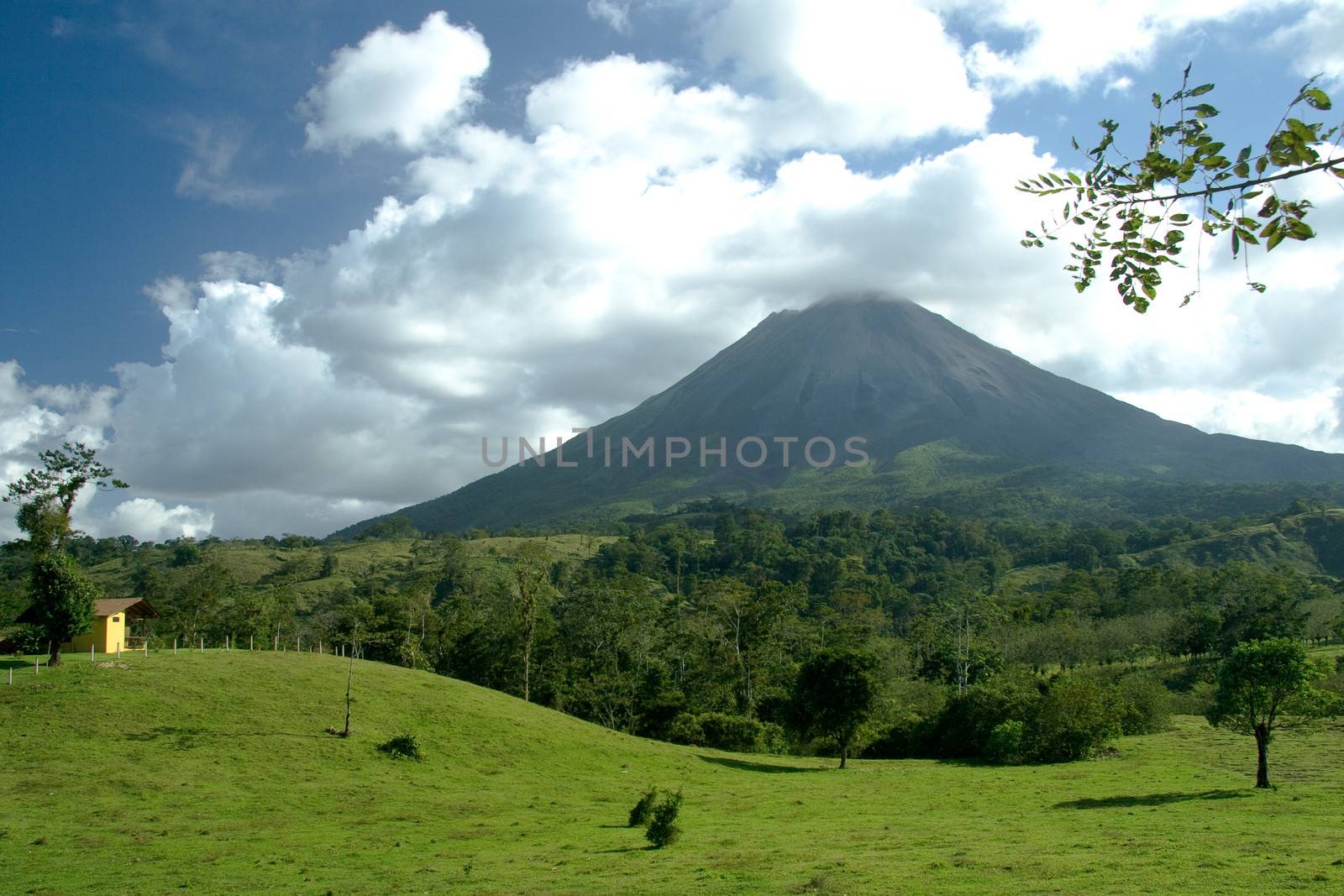 Scenic view of Arenal volcano with green countryside in foreground, Costa Rica.