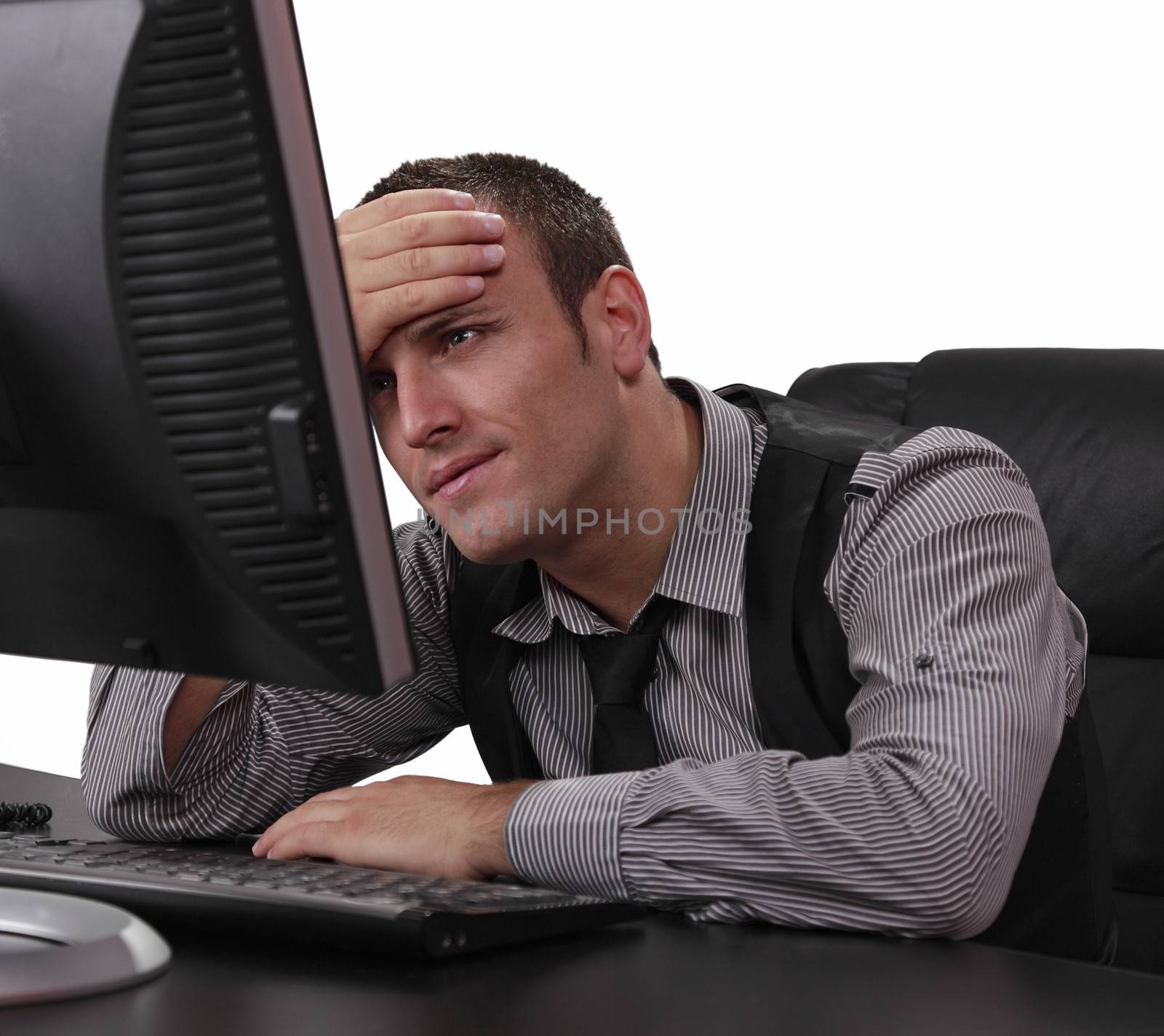 Unhappy young businessman in front of his computer at the office.