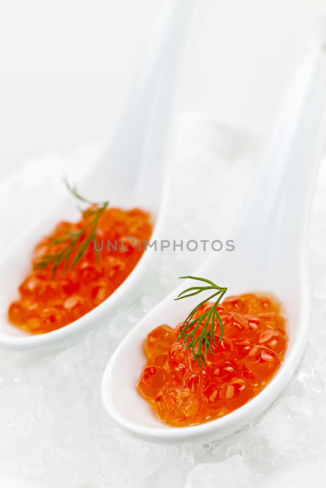 Closeup of caviar with dill garnish in two white spoons on ice