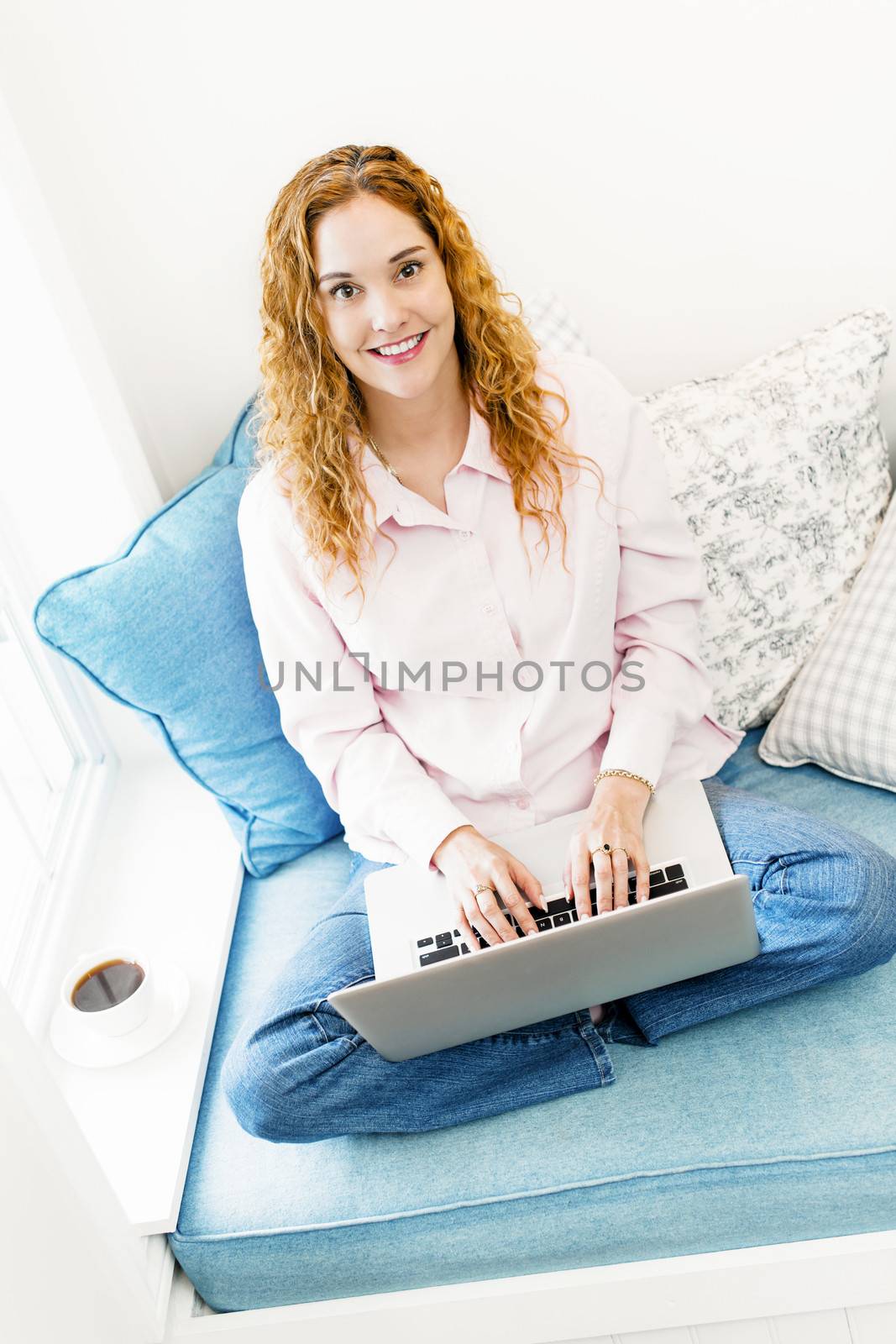 Caucasian woman with laptop computer looking up sitting on couch at home