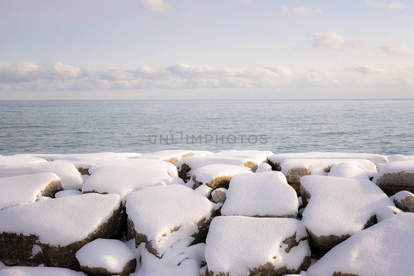 Rocks under snow on winter shore of lake Ontario in Sylvan park Toronto