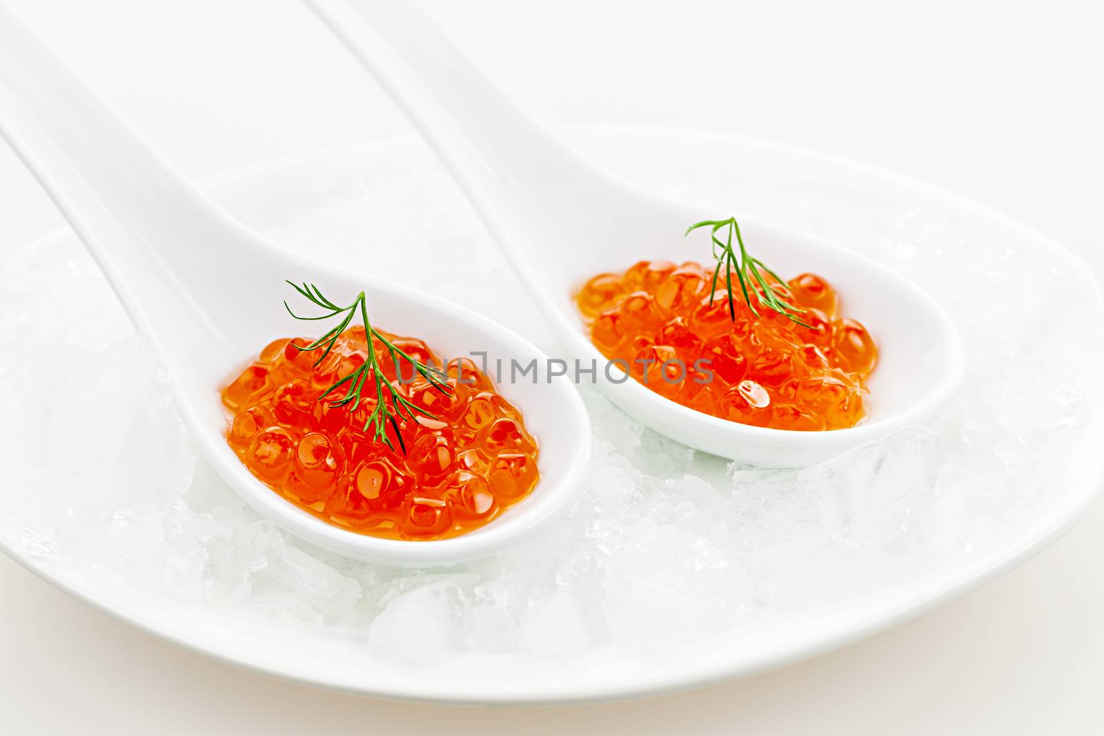 Closeup of caviar with dill garnish in two white spoons on ice