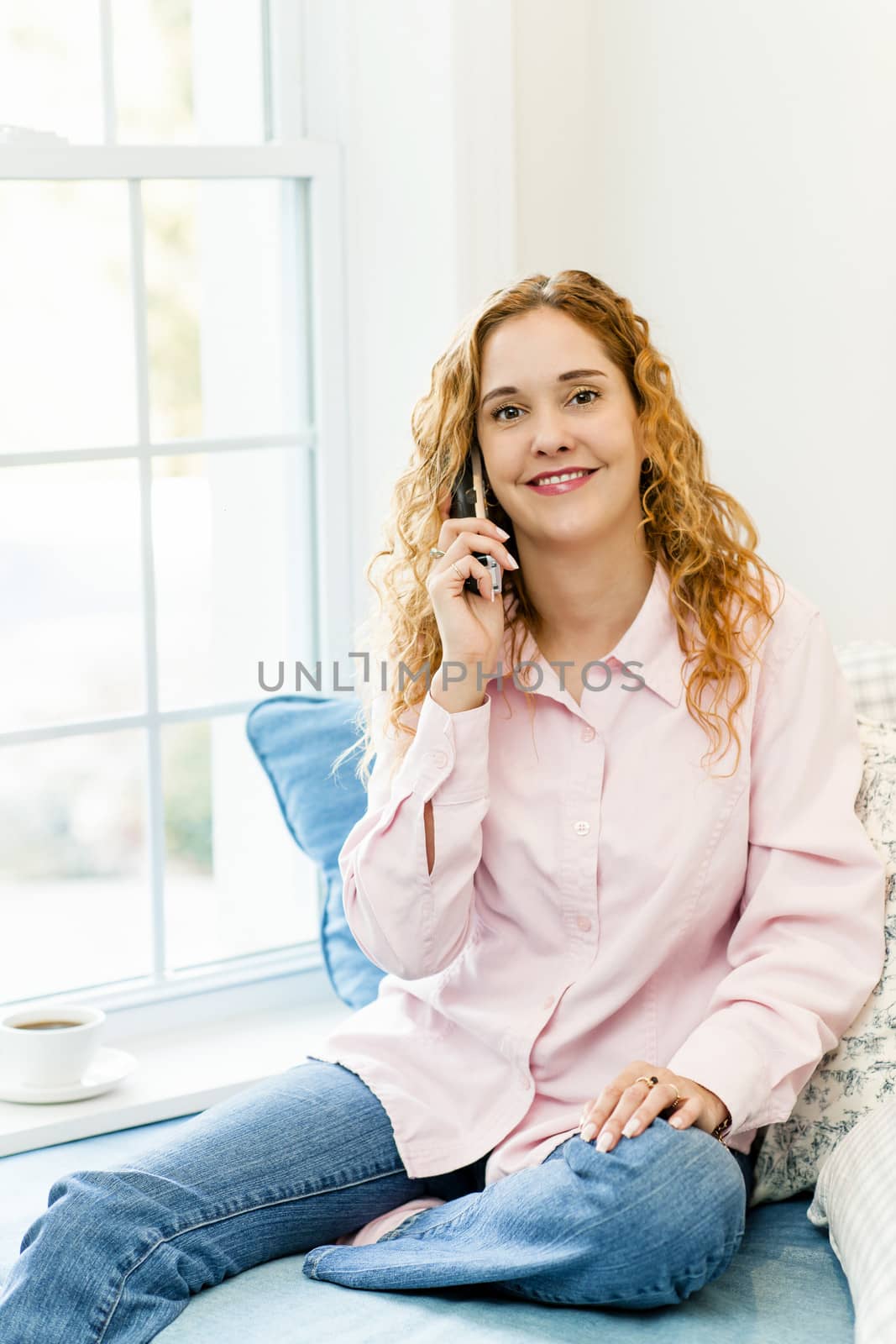 Smiling caucasian woman talking on cordless telephone at home