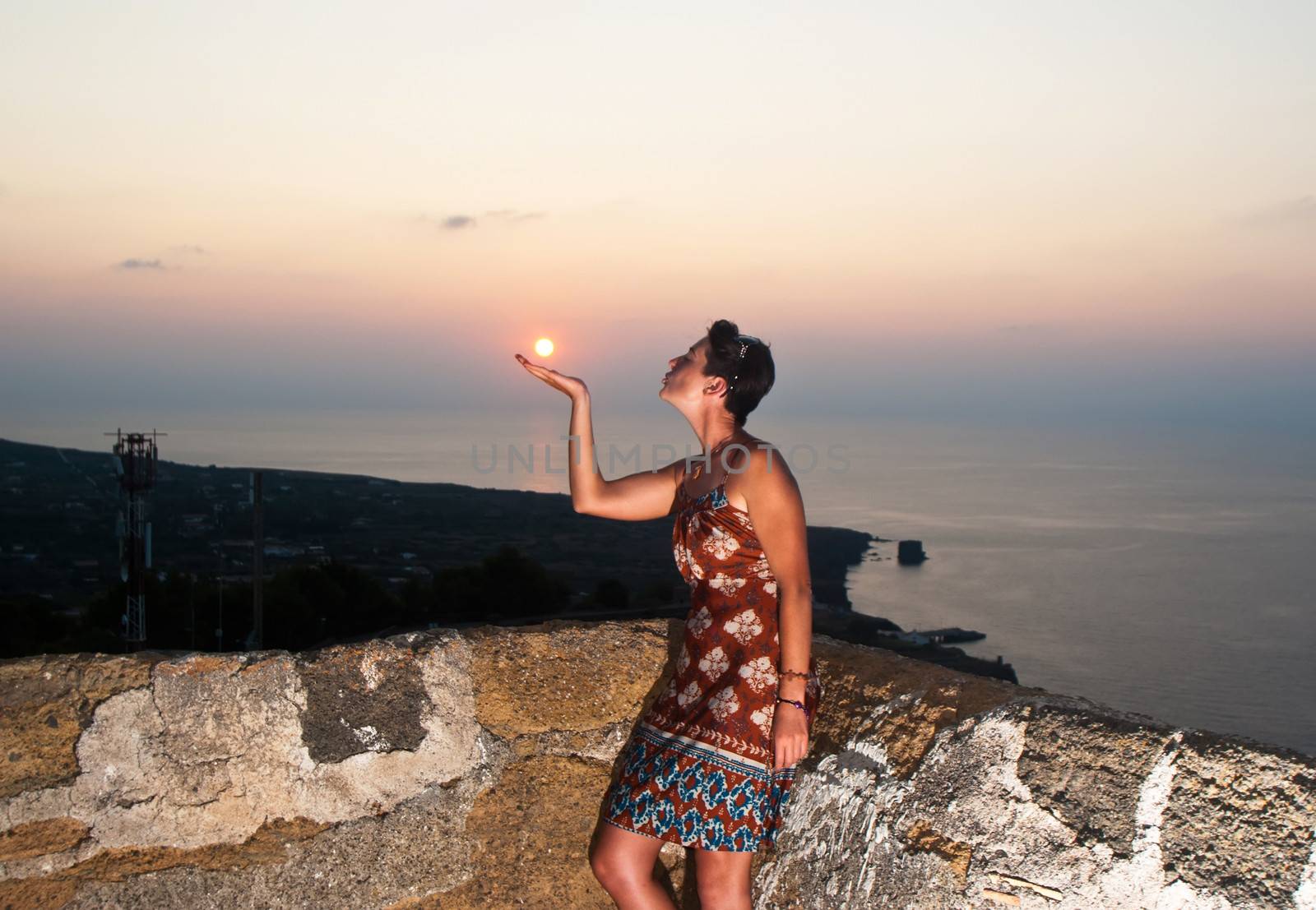 Beautiful girl kisses the sun at sunset on the island of Ustica, Sicily