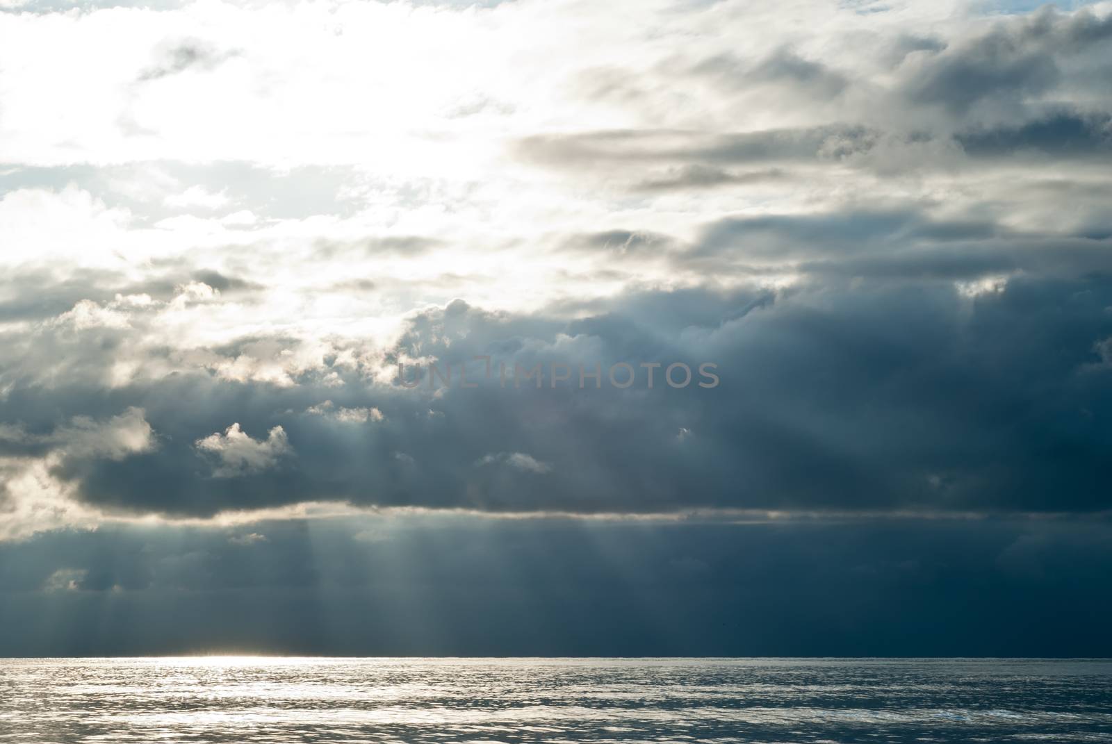 The sun's rays passing through the storm clouds over the sea