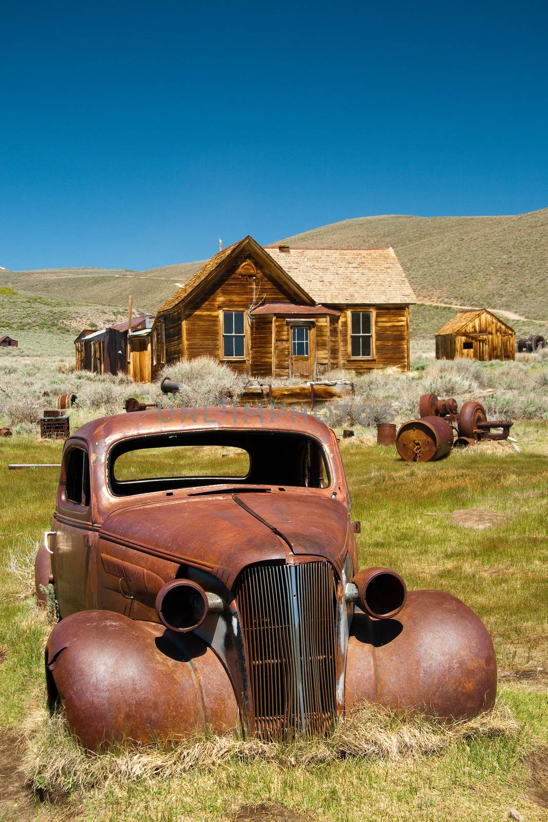 Log cabins and an abandoned decaying car  at Bodie State Historic Park  a Californian gold-mining ghost town.