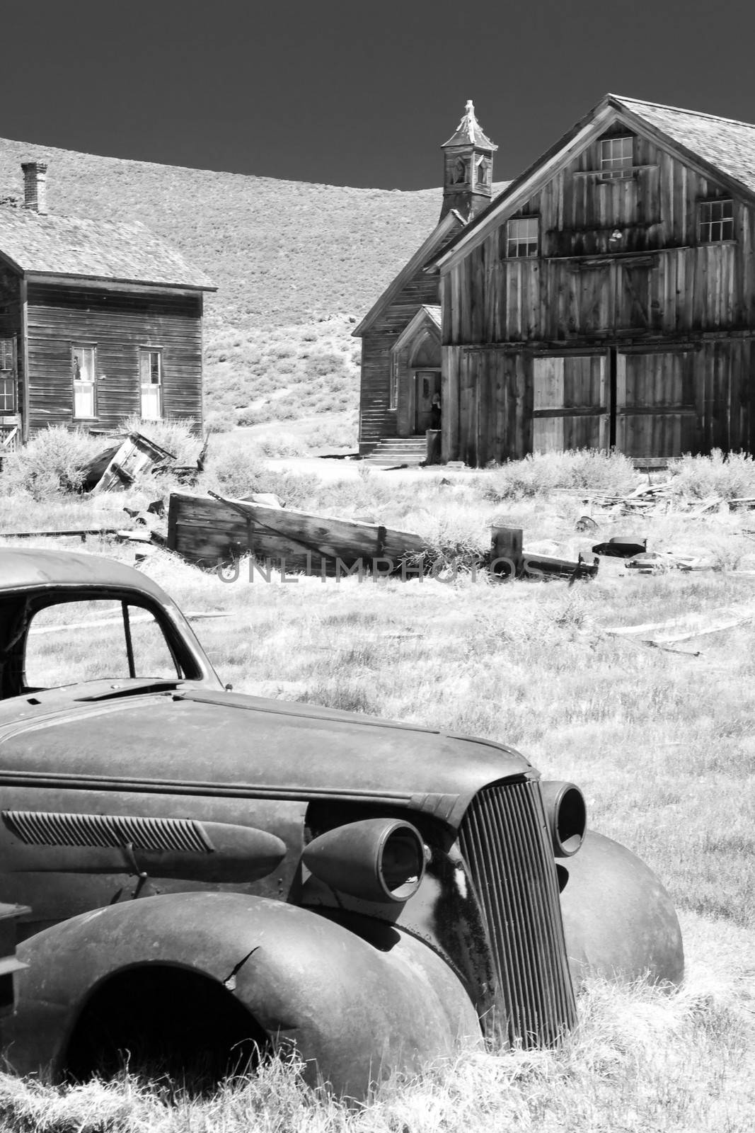 Abandoned car and historic wooden buildings in Bodie State Historic Park a Californian gold-mining ghost town.