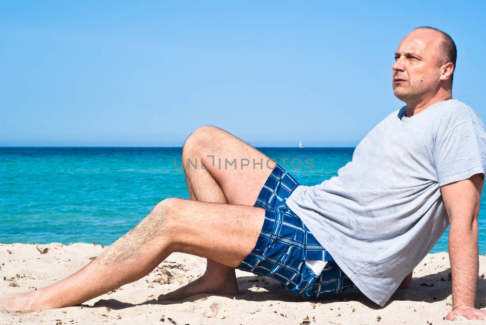 Natural outdoor portrait of man sitting on the beach to relax