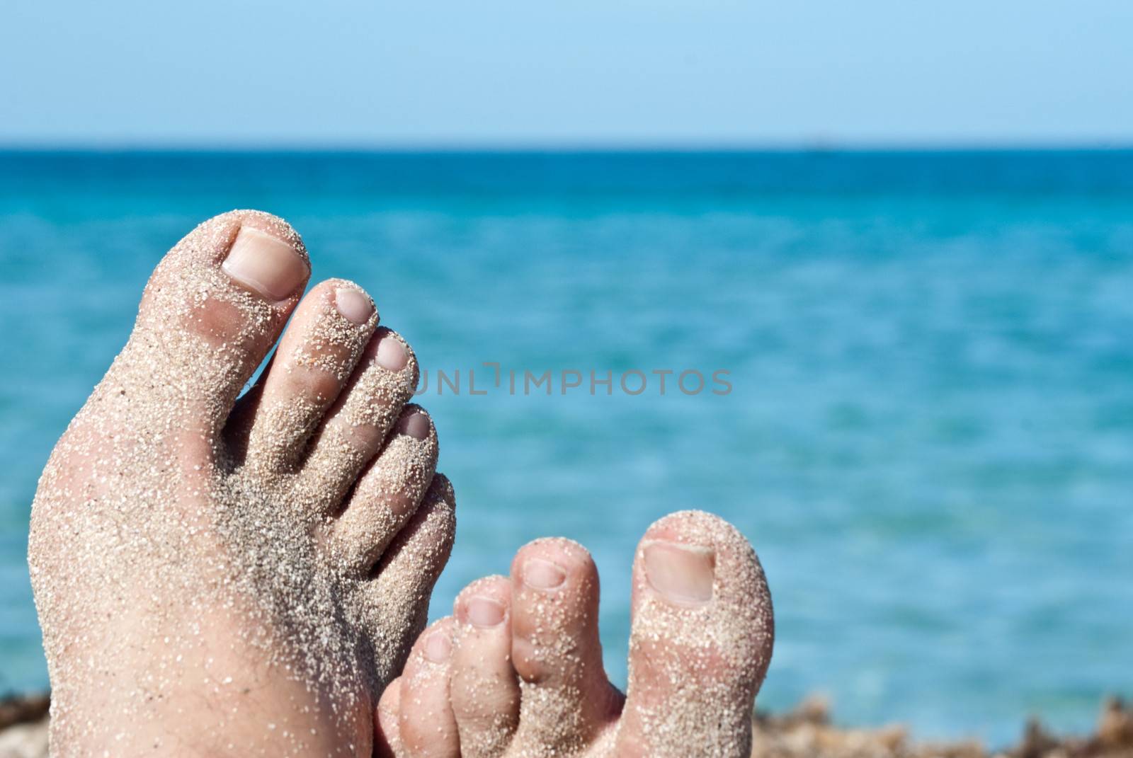 male feet over tropical beach background