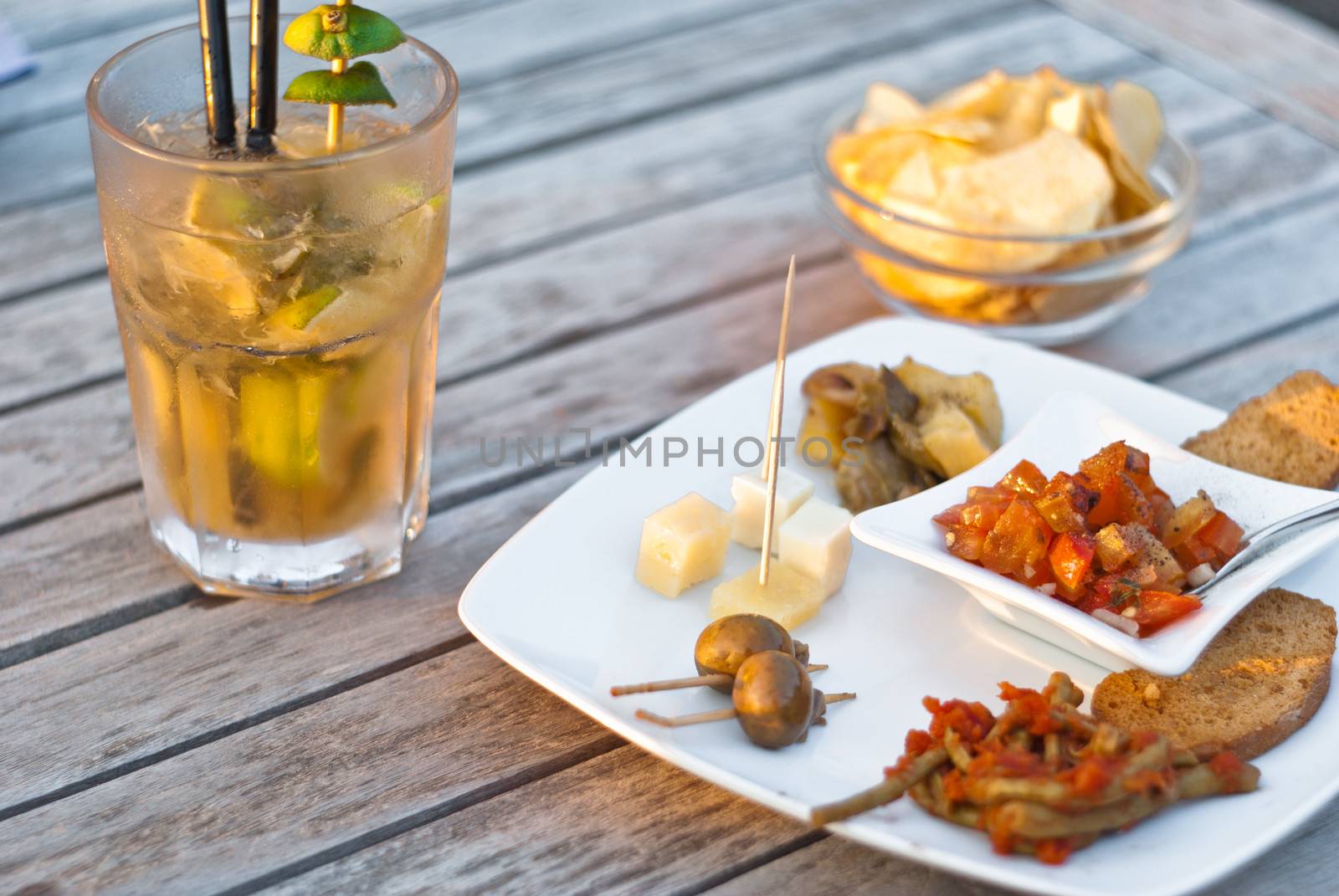 mojito cocktail with snacks on wooden table by gandolfocannatella