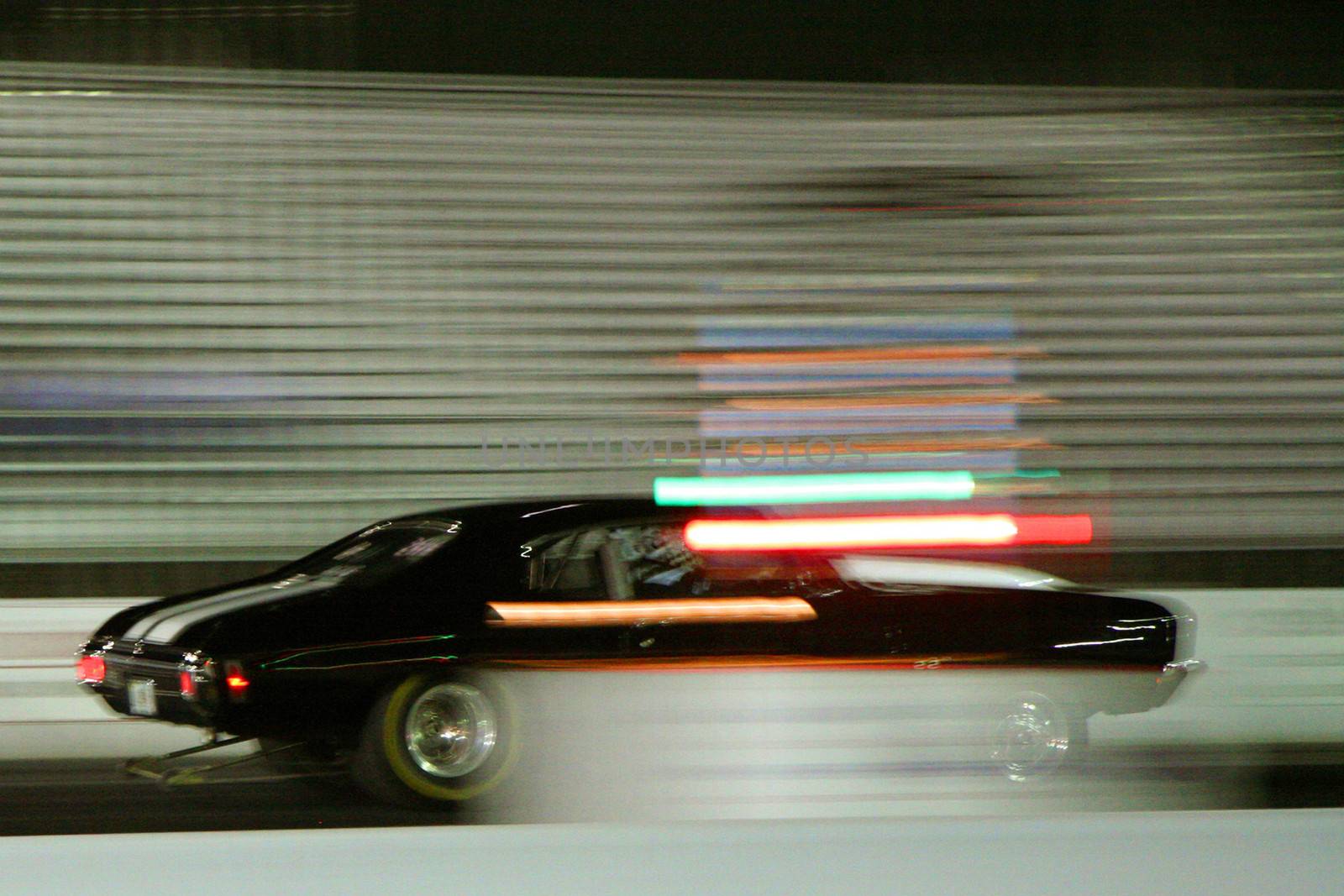 Side view of black car racing with abstract light effect.