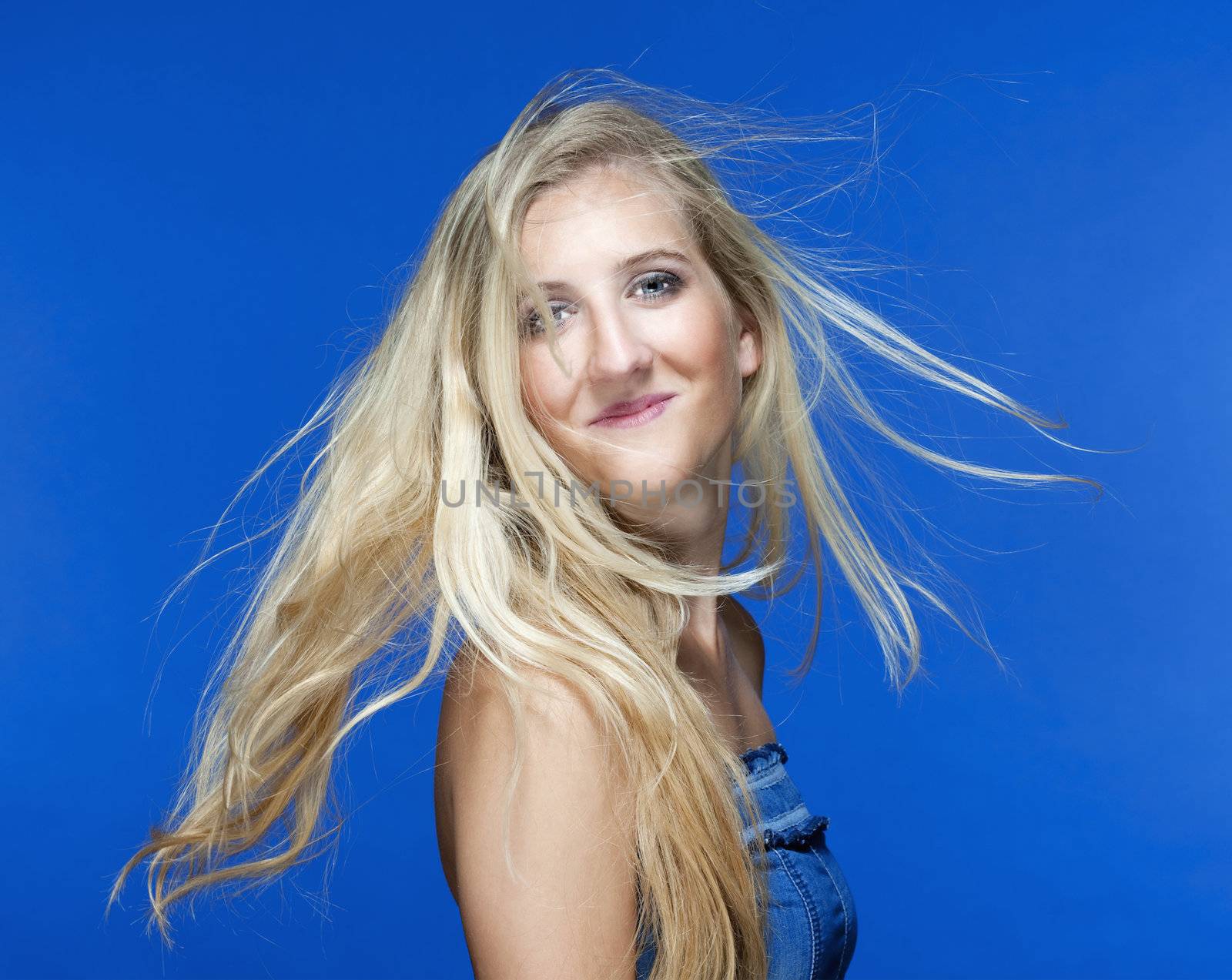 portrait of a young woman with blond hair - isolated on blue