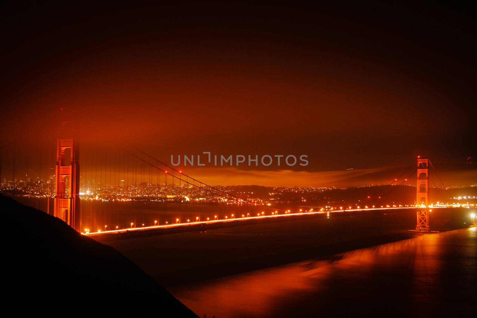 Golden Gate Bridge at night with some fog and city lights. San Francisco, United States of America.