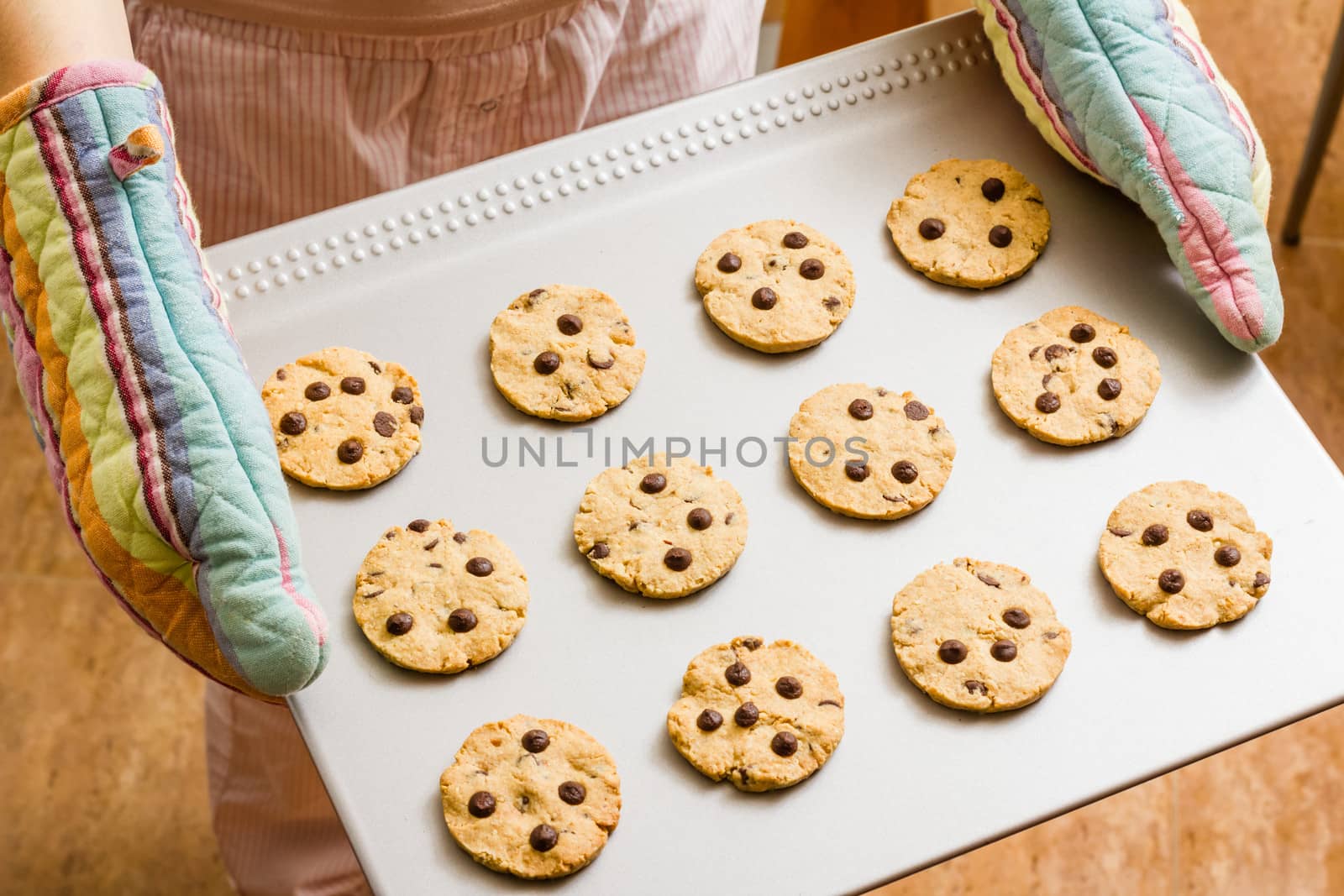 Woman with colorful kitchen gloves holding a homemade baked cookies tray