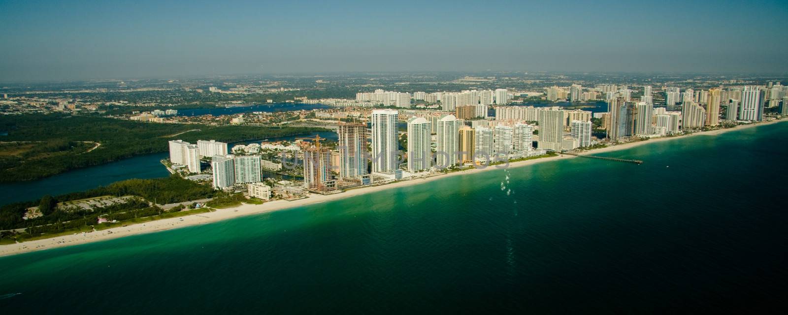 An aerial view of the seashore in Miami with deep green and blue waters.