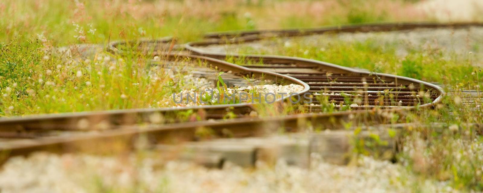 Panoramic view of old railway track in green grass.