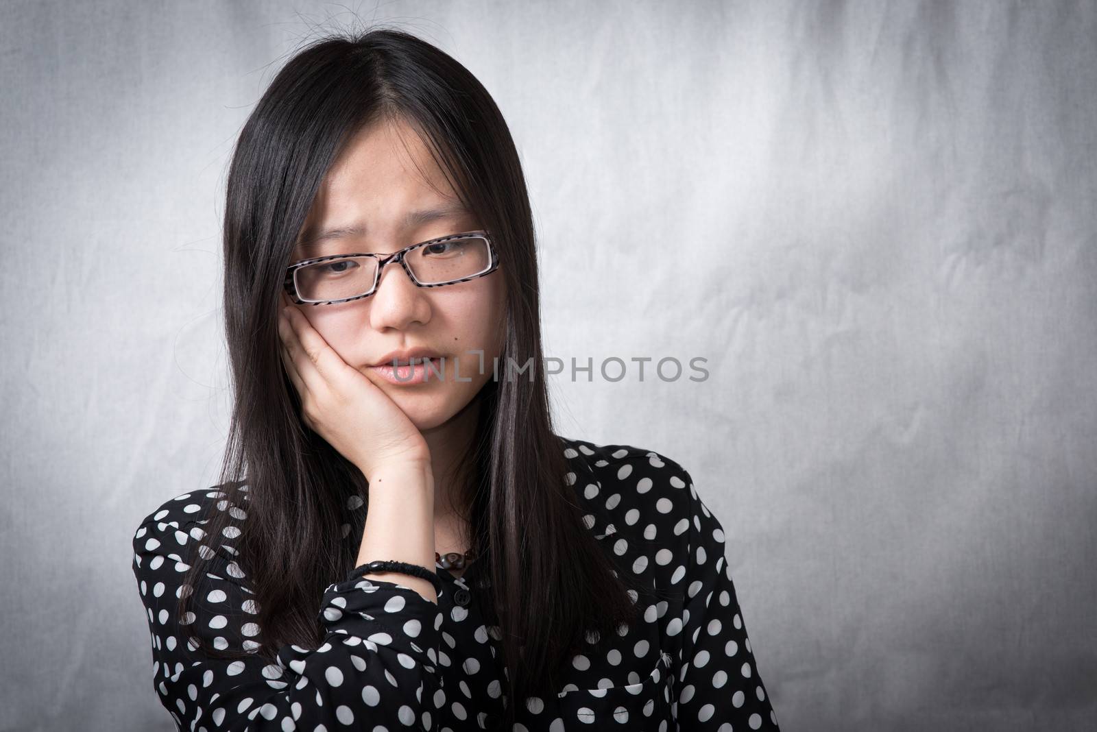 Depressed girl holding her face and looking deep in thought