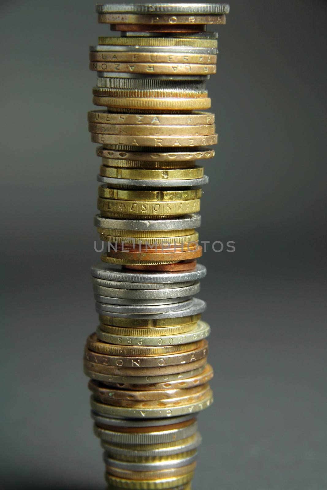 Tall stack of coins from different countries.