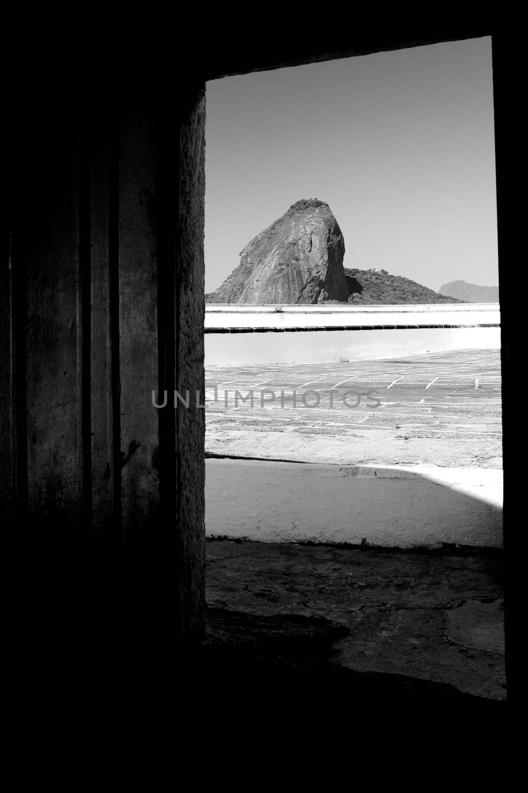 Black and white scenic view of Sugarloaf mountain viewed from doorway of Santa Cruz fortress, Niteroi, Brazil.