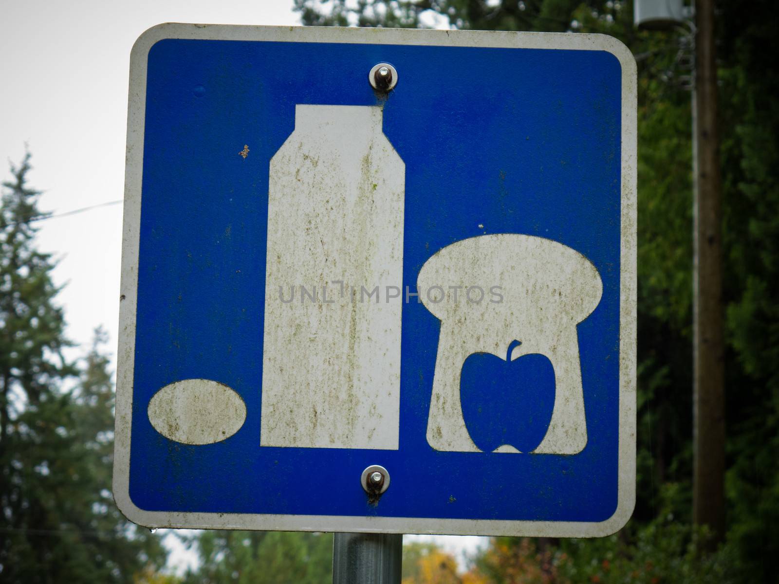 Weathered road sign picturing basic food staple such as milk  bread  apple and egg