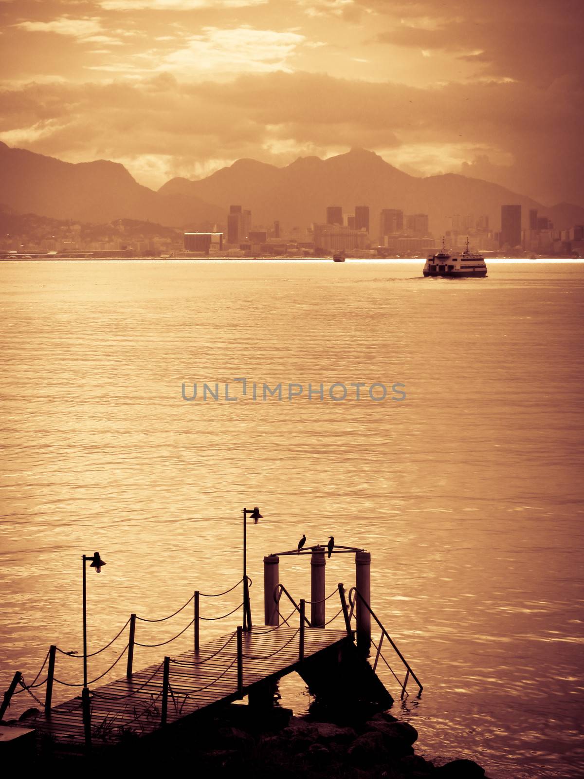 Golden sunset over Rio de Janeiro city skyline with pier in foreground, Brazil.