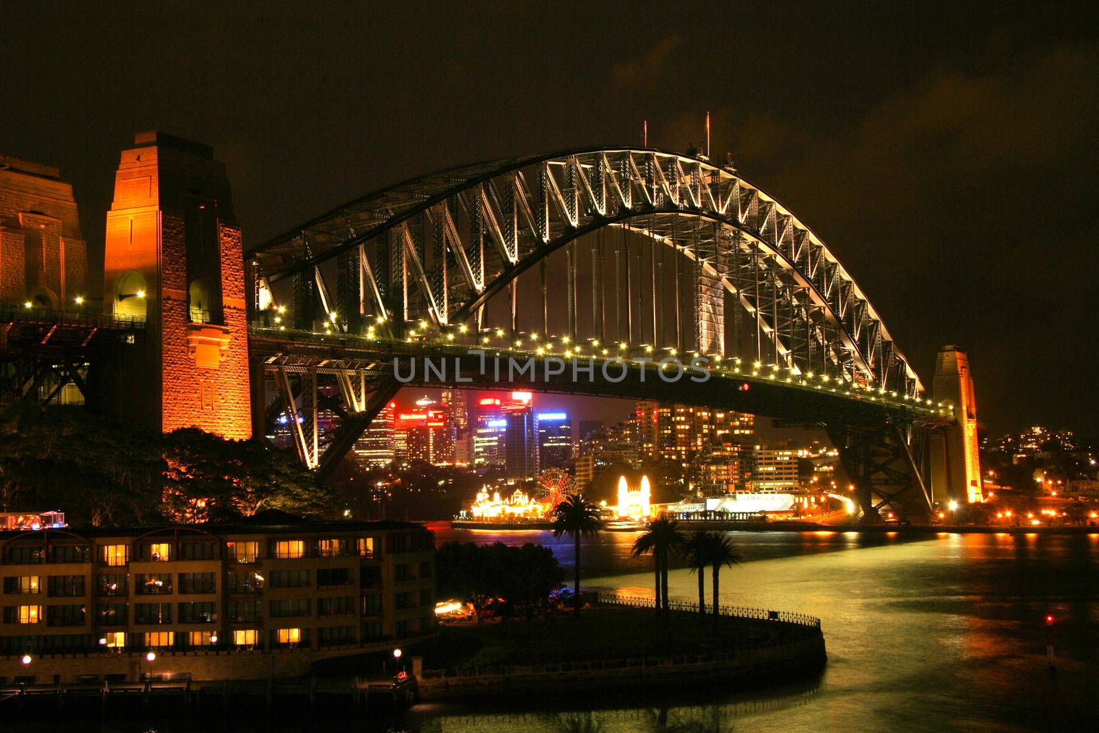 The Sydney Harbour Bridge illuminated at night with lots of city lights on the background.