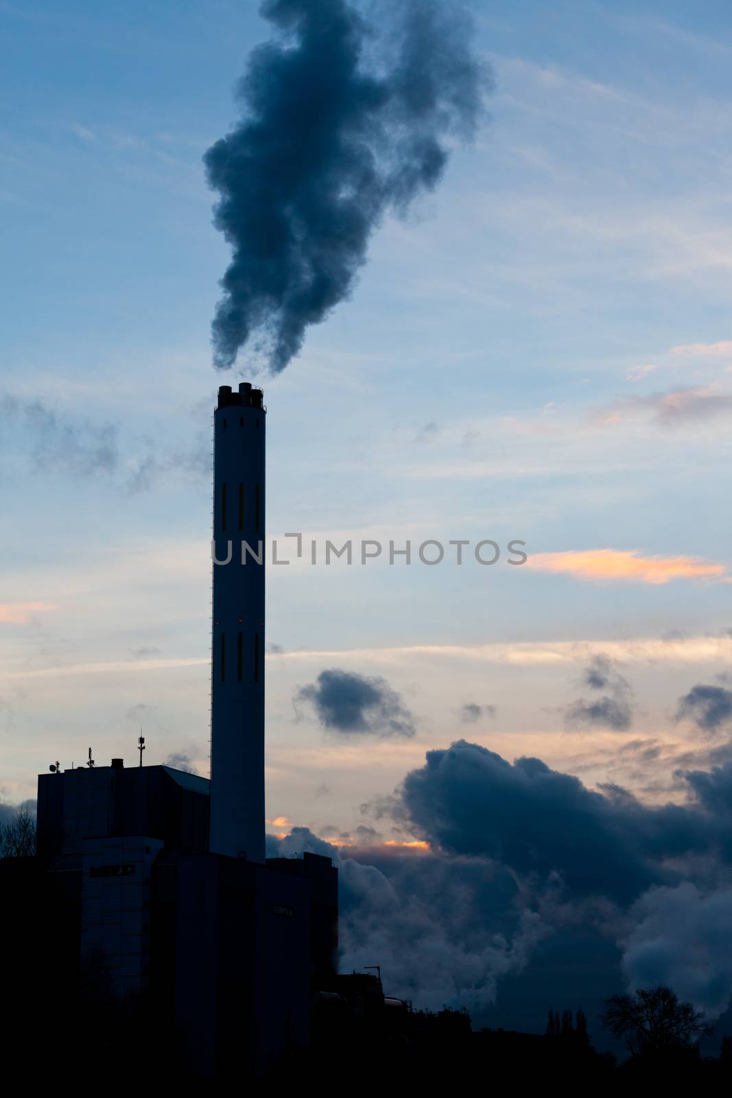 Smokestack chimneys belching black smoke pollutants and carbon dioxide greenhouse gas into the atmosphere polluting and contributing to global warming