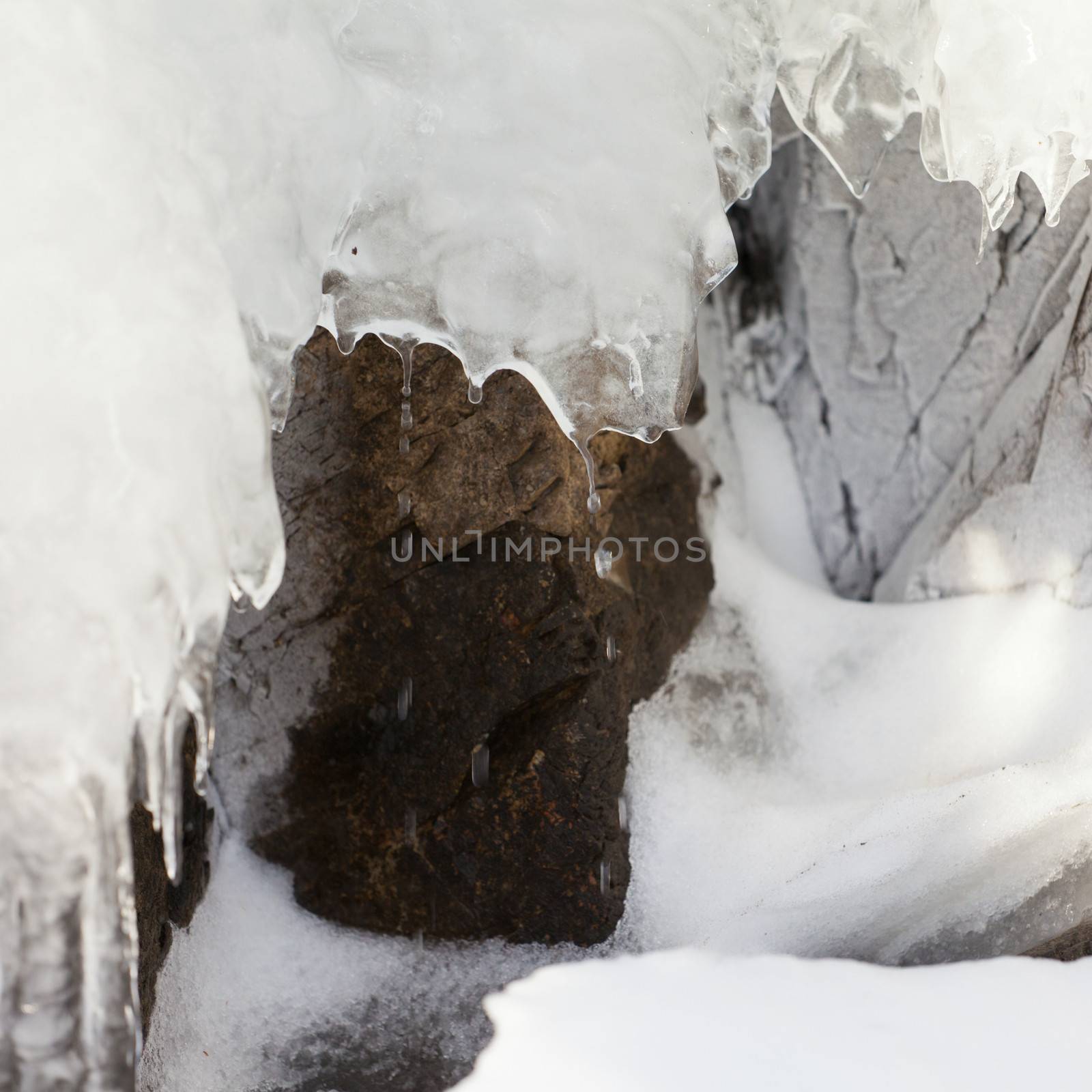 Snow and ice on weathered surface of frost-fractured rock thaw quickly dripping water drops