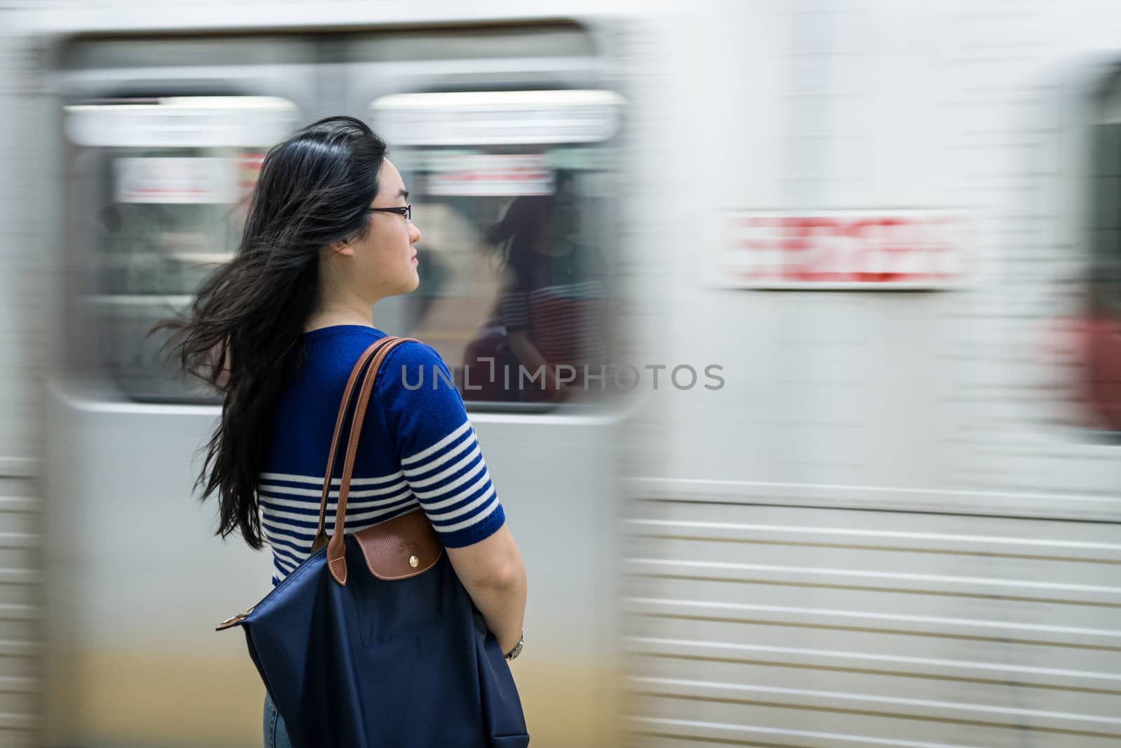 Young woman waiting at subway station with moving train