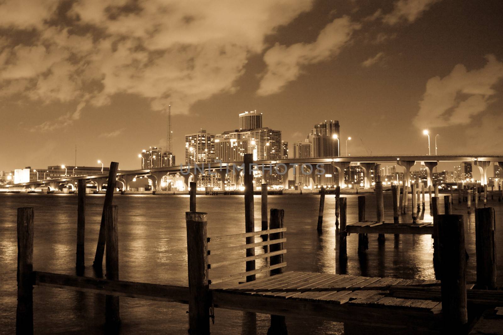 A little wooden old and rotten pier with the lights of the Miami city as a background.