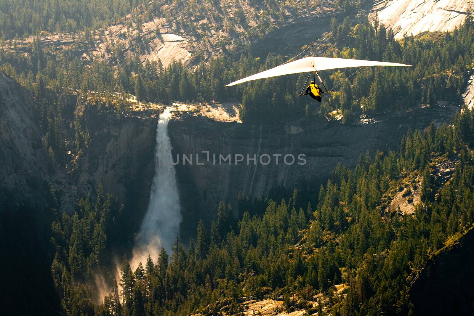Aerial view of waterfall and forest in Yosemite National Park with hang glider in foreground, viewed from Glacier Point, California, U.S.A.