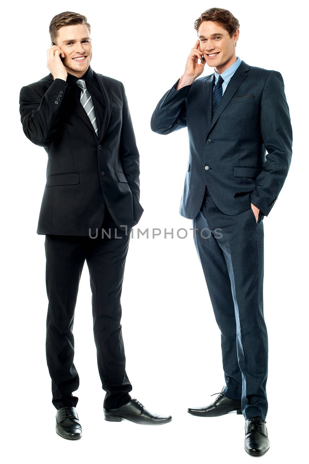 Two businessmen talking on cellphone by stockyimages