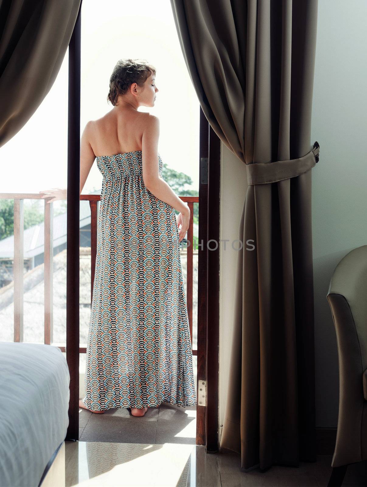 Pretty woman in long dress standing on a balcony 