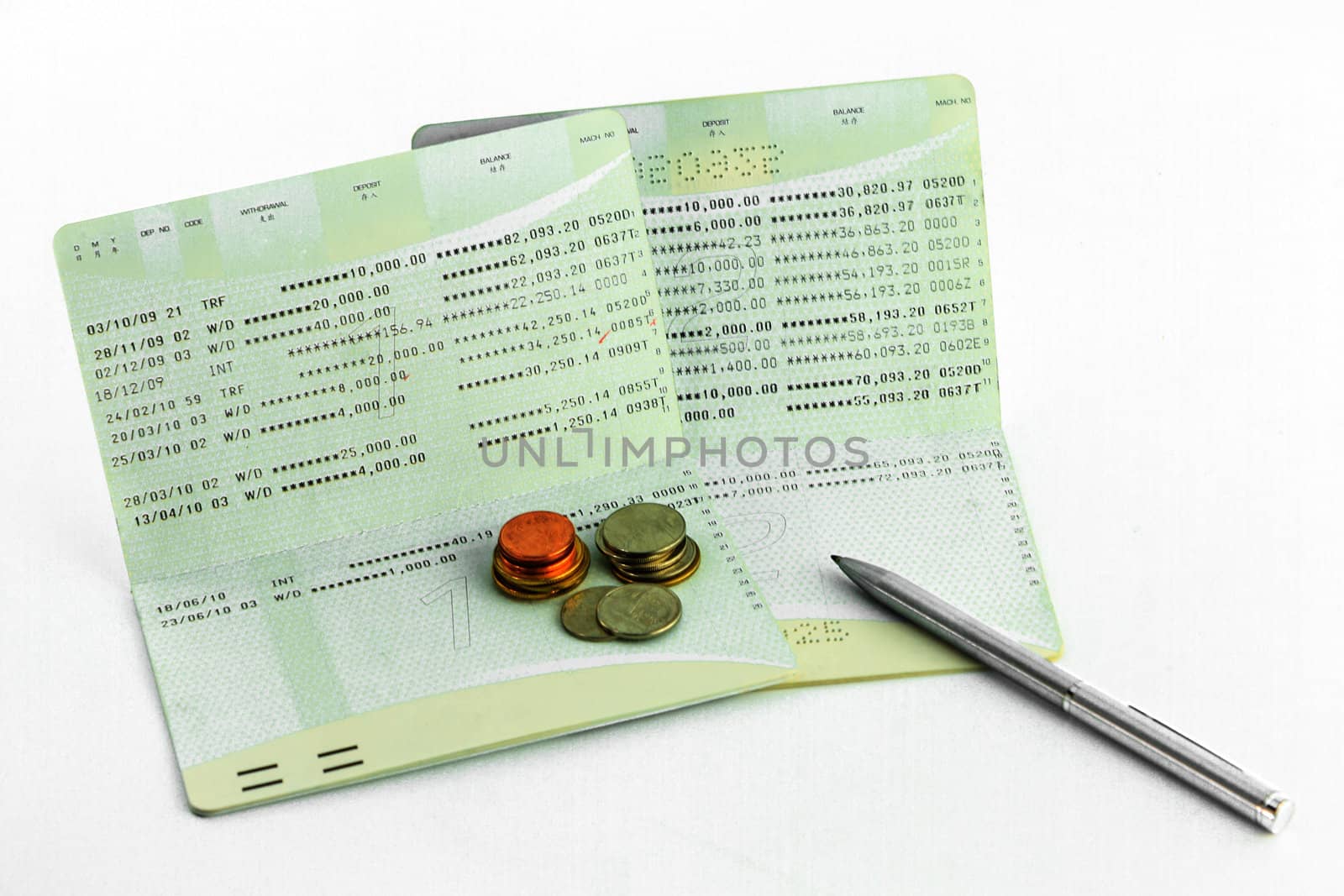 Coins on account passbook with pen isolate on white background