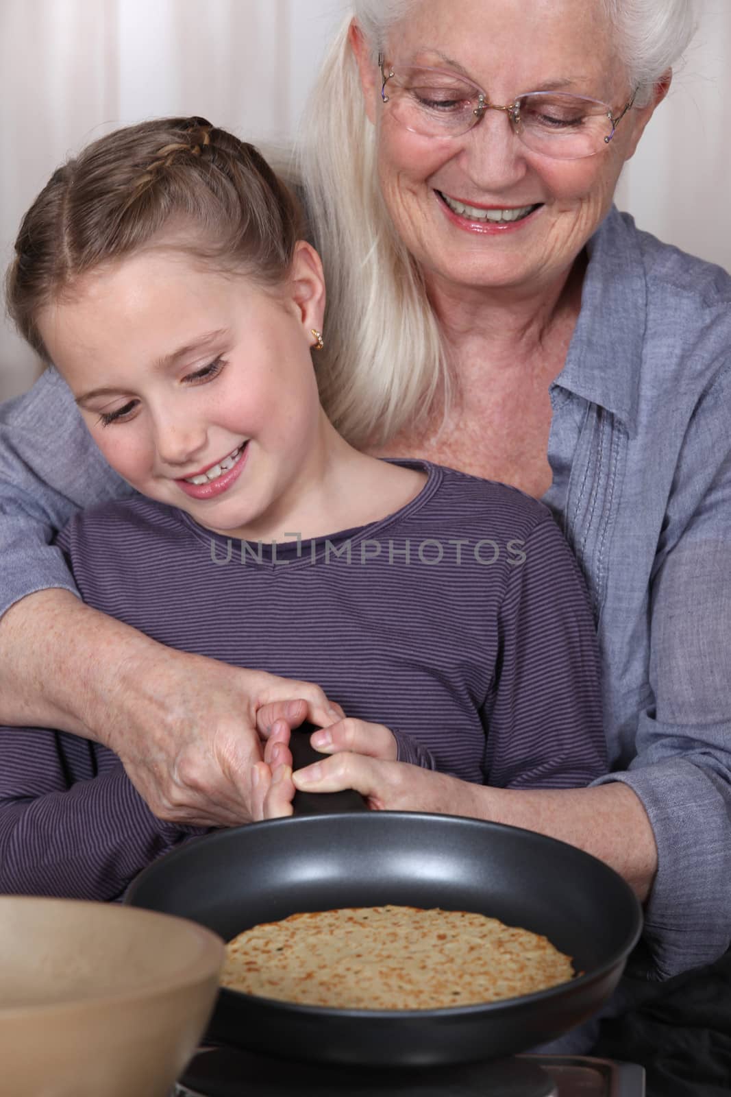 Girl and her granny cooking pancakes