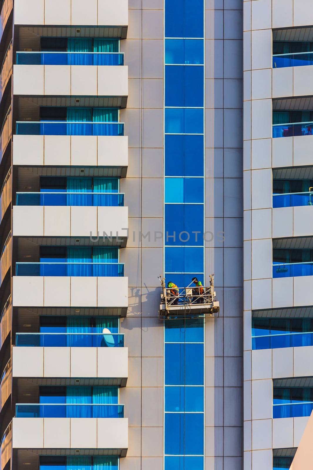 window cleaners in a gondola cleaning the windows of a corporate office skyscraper.