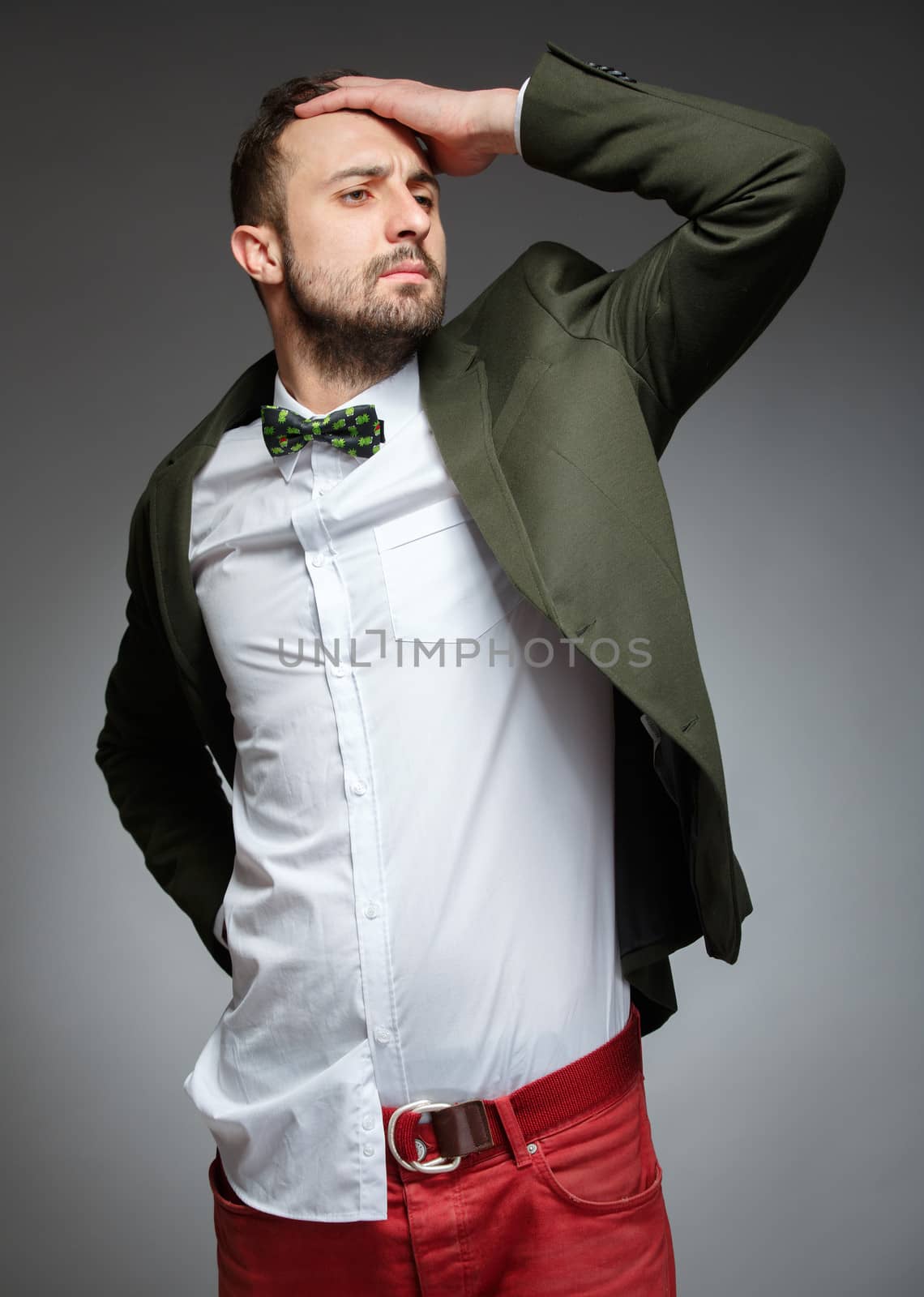 Portrait of handsome stylish man in elegant green suit. Grey background.