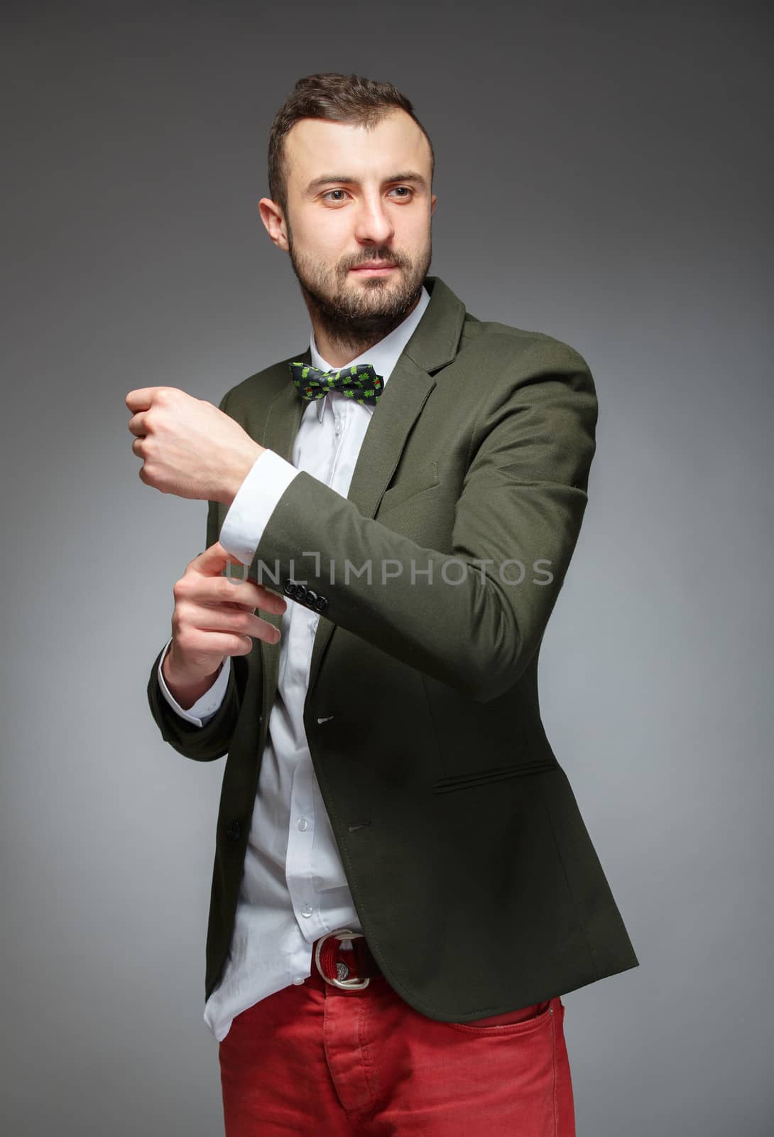 Portrait of handsome stylish man in elegant green suit. Grey background.