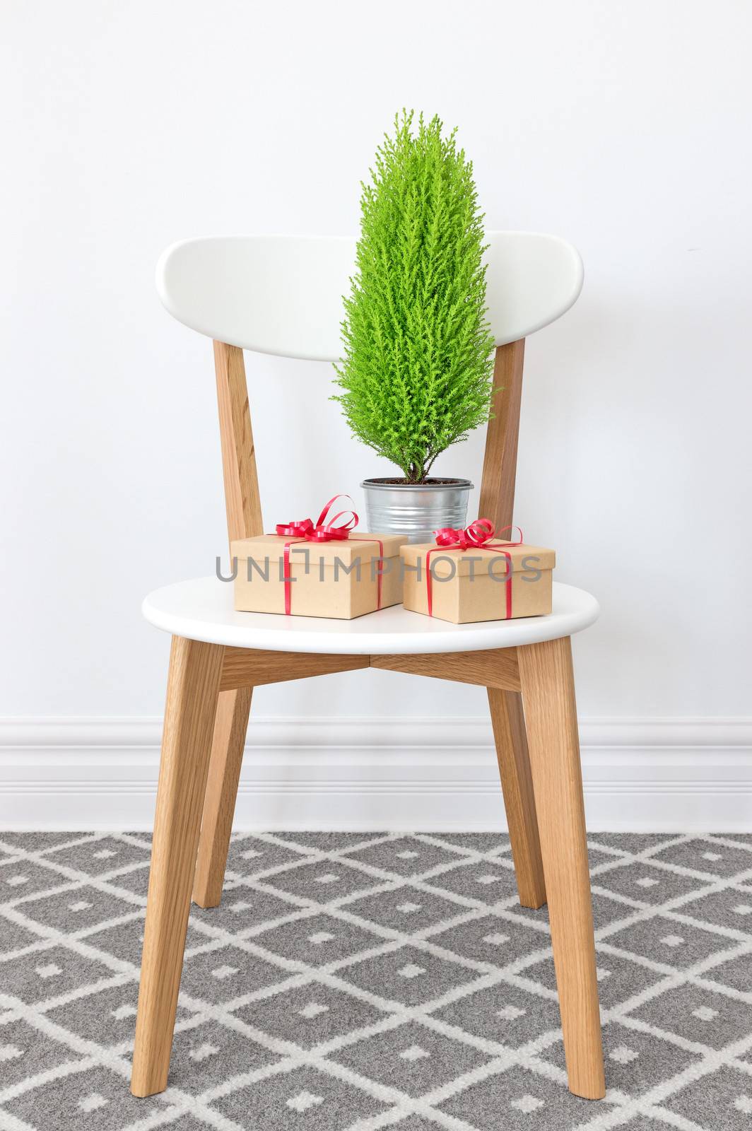 Presents and little green cypress tree on an elegant white chair.