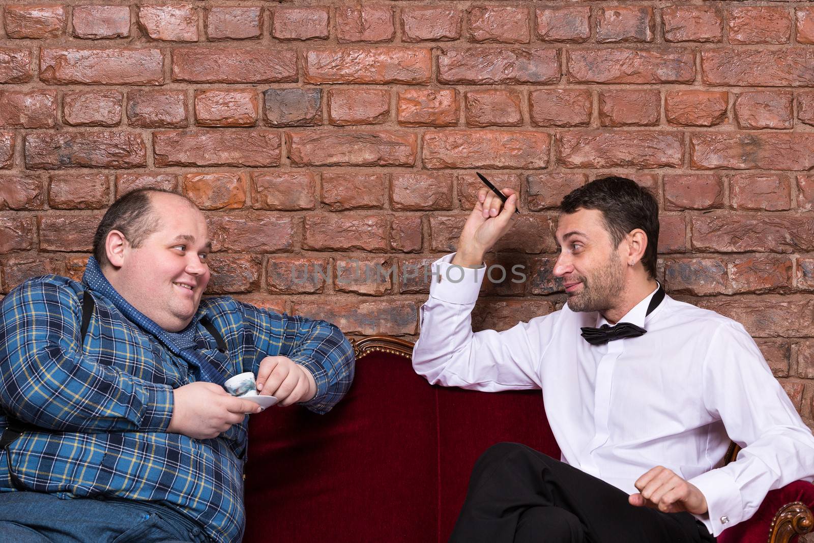 Elegant man sitting with an overweight country yokel