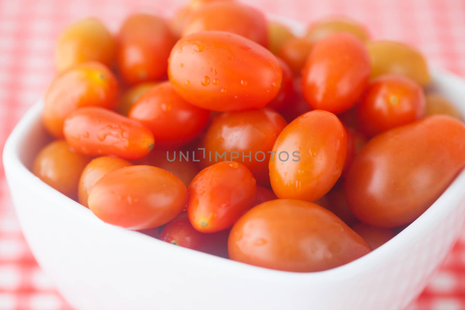 cherry tomatos in bowl on checkered fabric by jannyjus